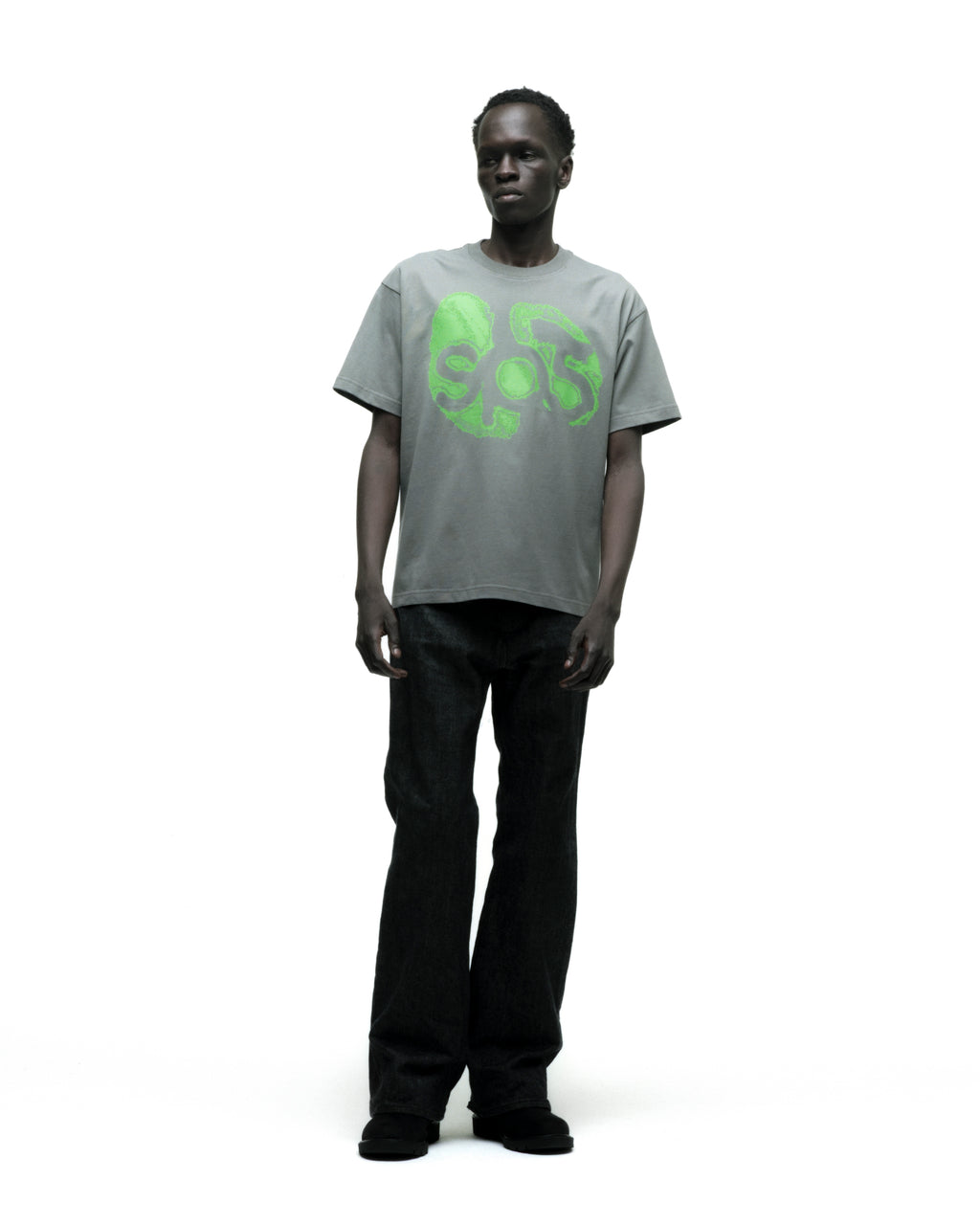 Man in a grey cotton FINGERPRINT TEE with a vibrant green graphic print, paired with dark jeans.