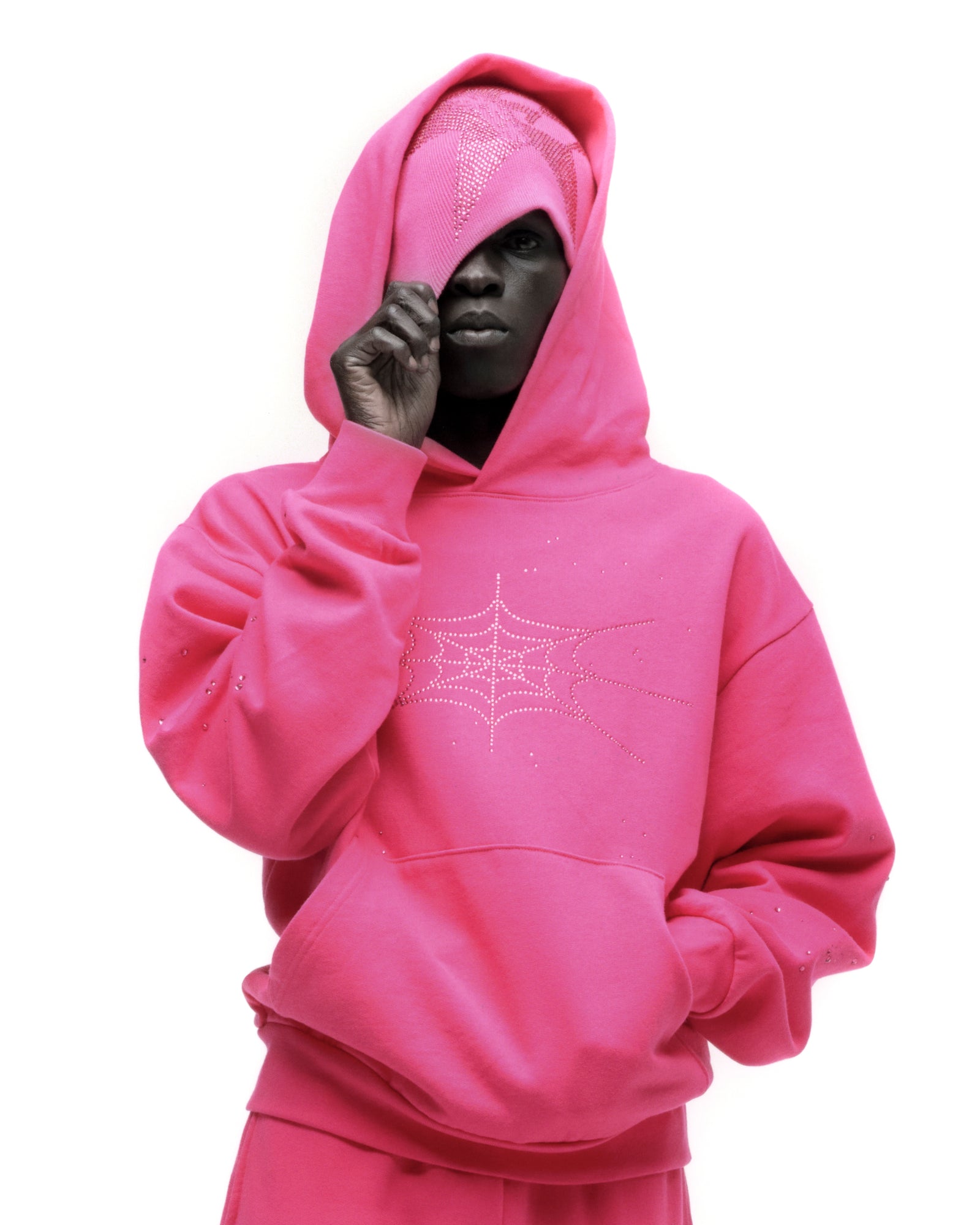 Pink rhinestone silk hoodie with spiderweb design, kangaroo pocket, and matching headwear.