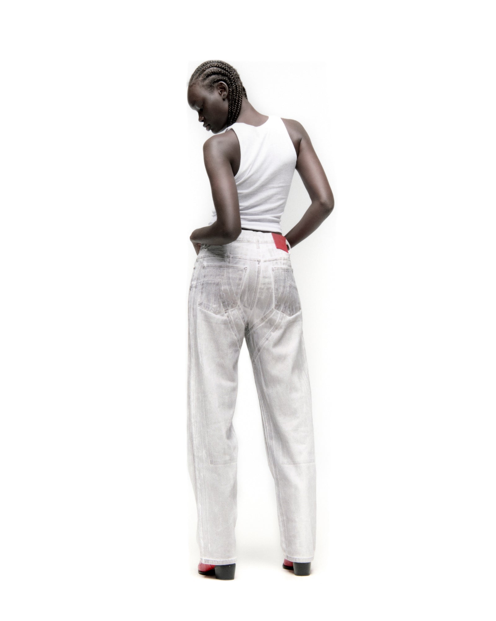 Model wearing platinum spray-effect wide-leg denim pants with panels and a red branded back patch.