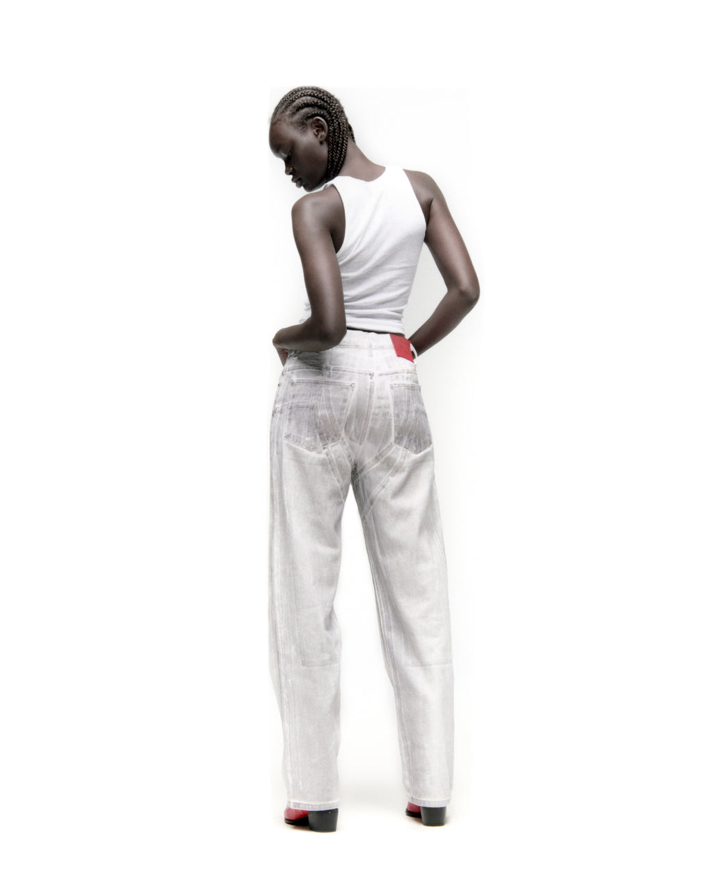 Model wearing platinum spray-effect wide-leg denim pants with panels and a red branded back patch.