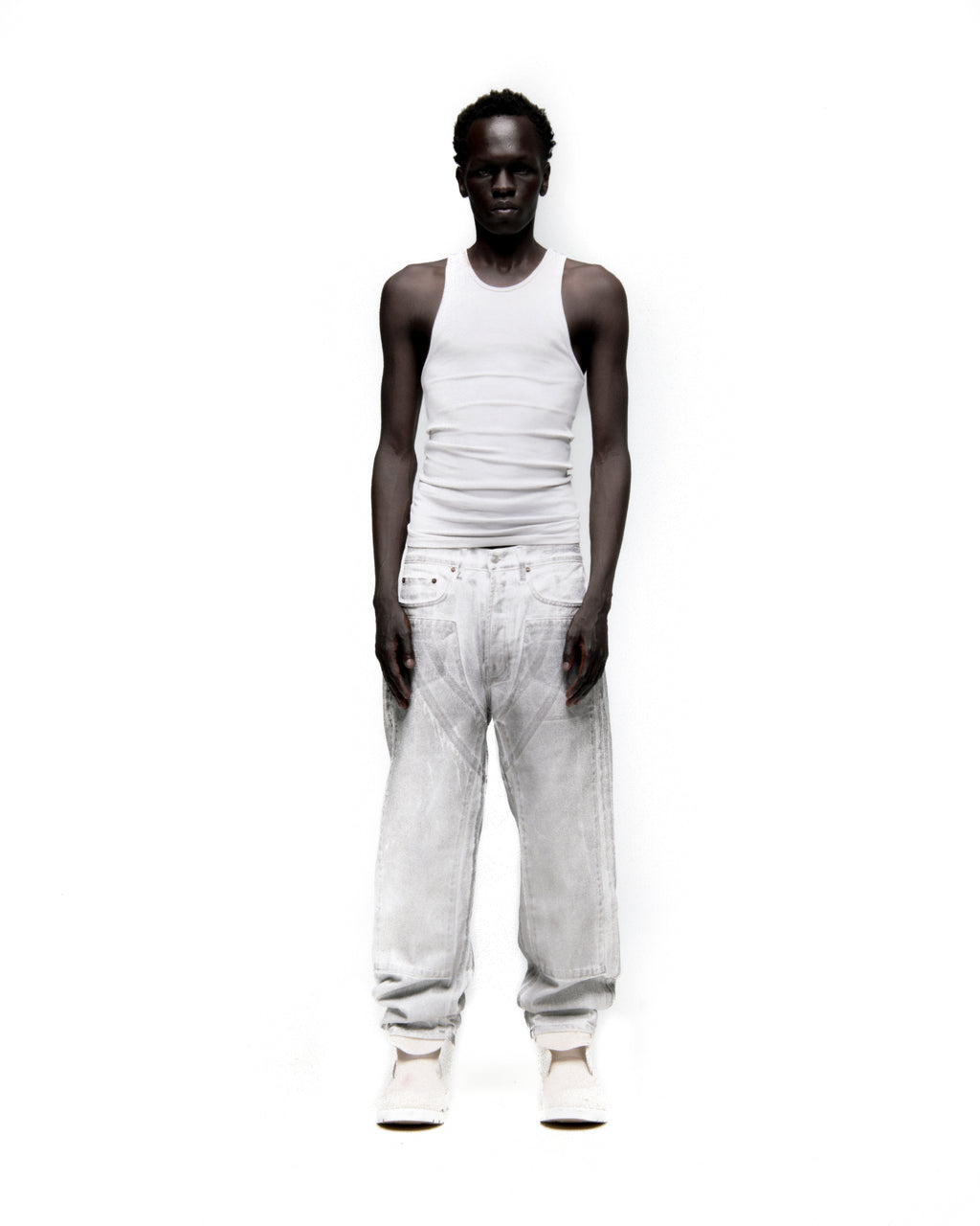 Man in Platinum Denim Pant, wide leg, spray-effect light wash, with front panels and white tank top.