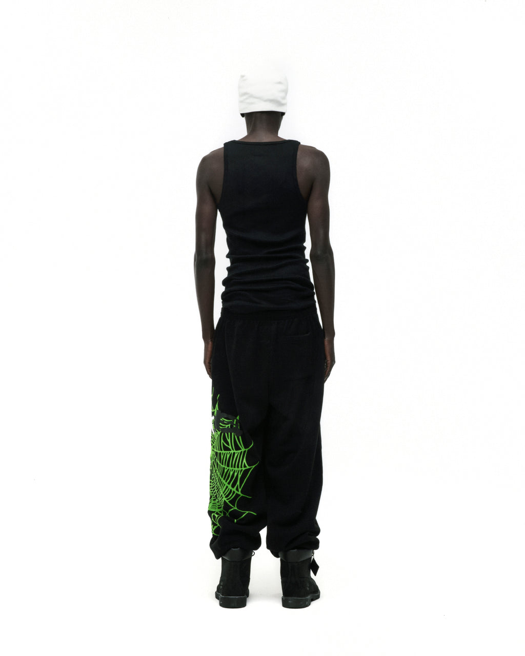 Black HEAVY WEB SWEATPANT with green SP5DER web graphic on leg, worn by a model from behind.
