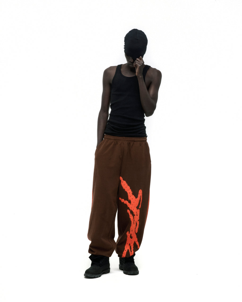 Brown cotton fleece sweatpants with orange sprayed-effect side stripe and wide-leg silhouette.