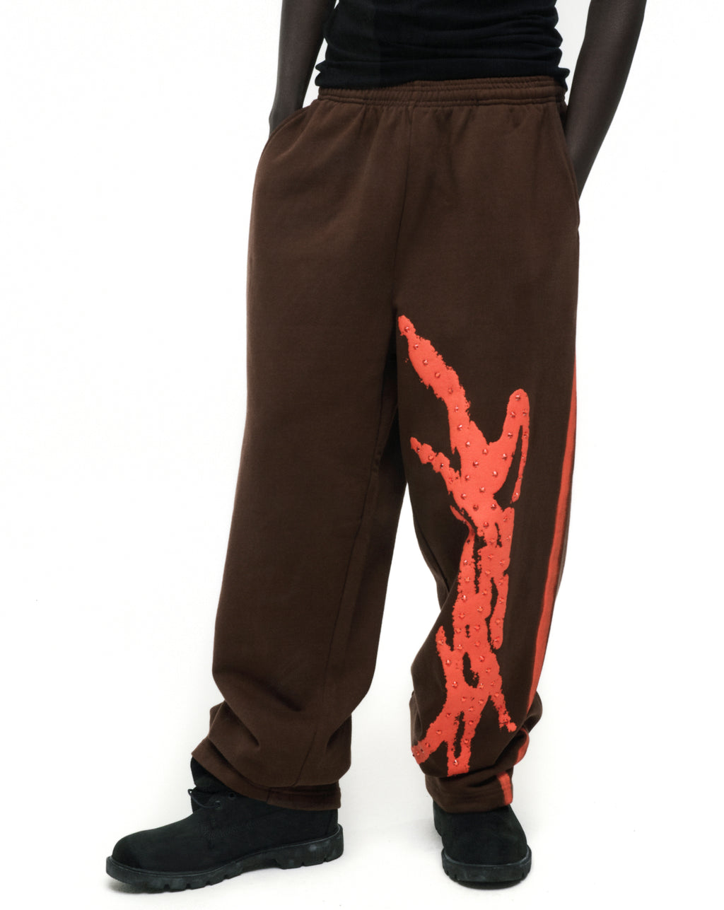 Brown cotton fleece sweatpants with red "SP5DER" logo, rhinestone accents, and sprayed-effect side stripe.
