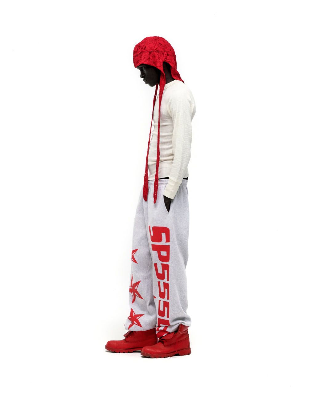 Grey MX555 sweatpants with red SP5DER logo and star print, wide-leg, worn by a model.