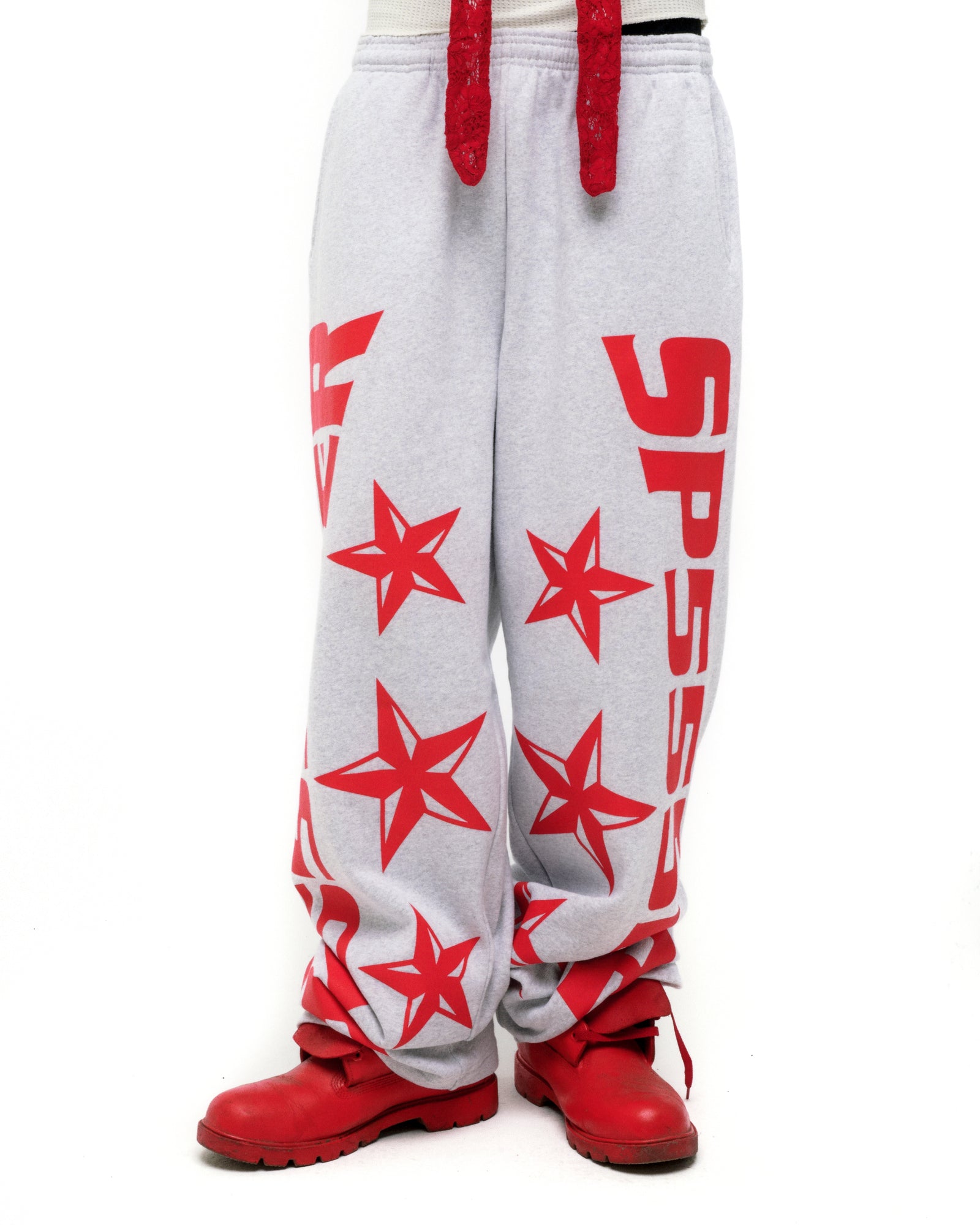 Grey MX555 sweatpants with red foil SP5DER logo, stars, drawstring, and wide-leg fit.