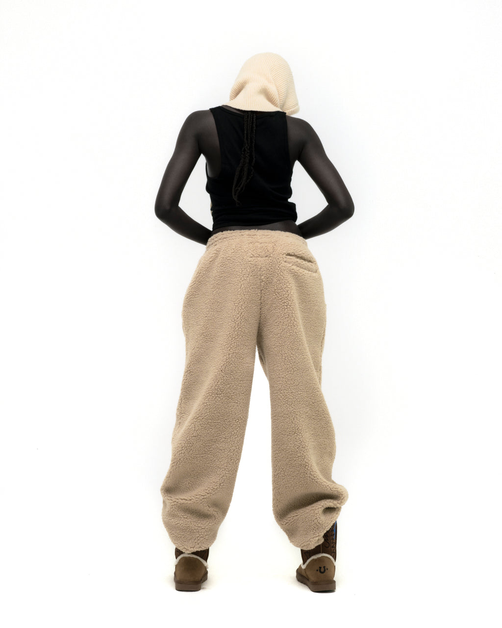 Model from behind wearing beige teddy fleece pants with a straight leg fit and brown boots.