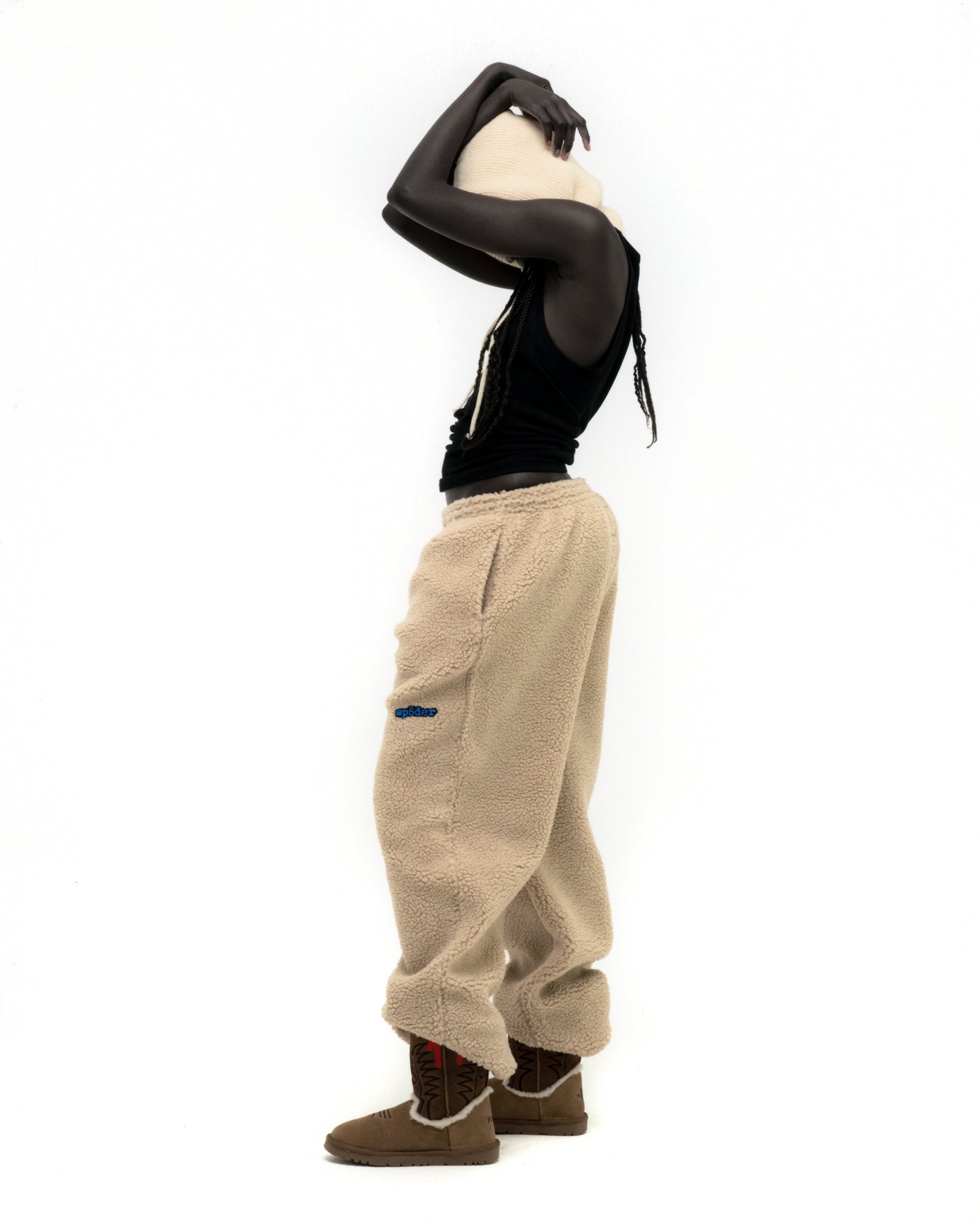 Beige teddy fleece pant with blue logo patch, worn by a model.