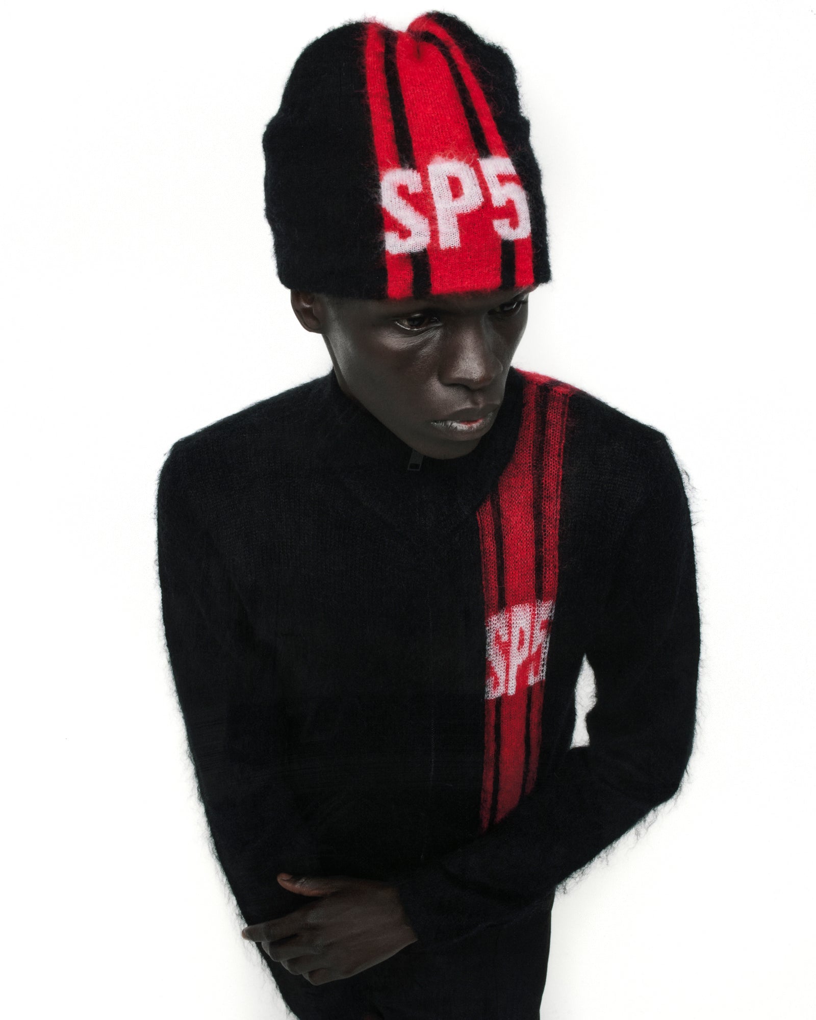 Black mohair knit zip sweater with red vertical stripes and "SP5" logo, paired with a matching beanie.