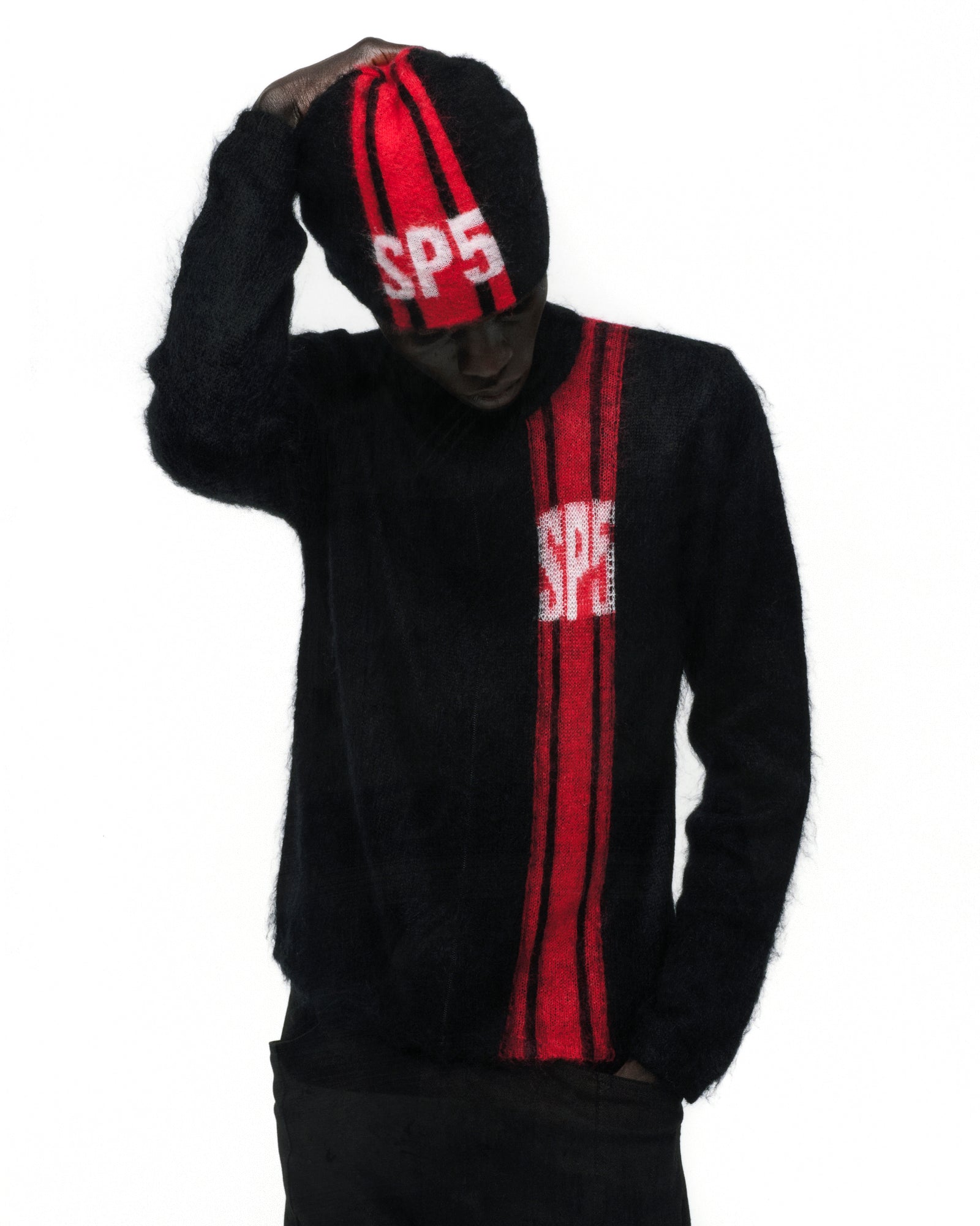 Black mohair knit beanie with red vertical stripe and "SP5" logo, worn with matching sweater.