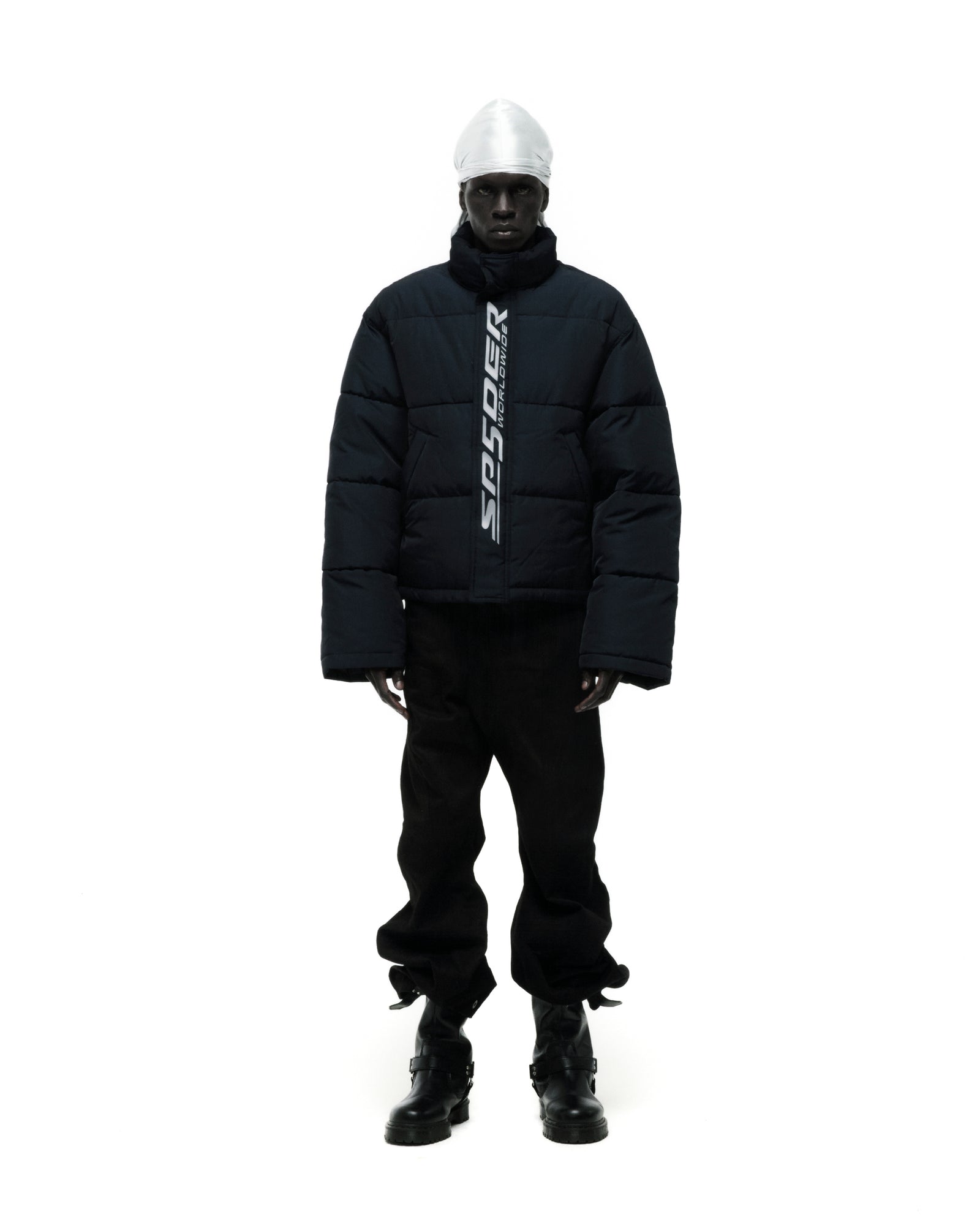 Dark blue TRACKHAWK puffer jacket with reflective "SP5DER WORLDWIDE" text, worn by a model.