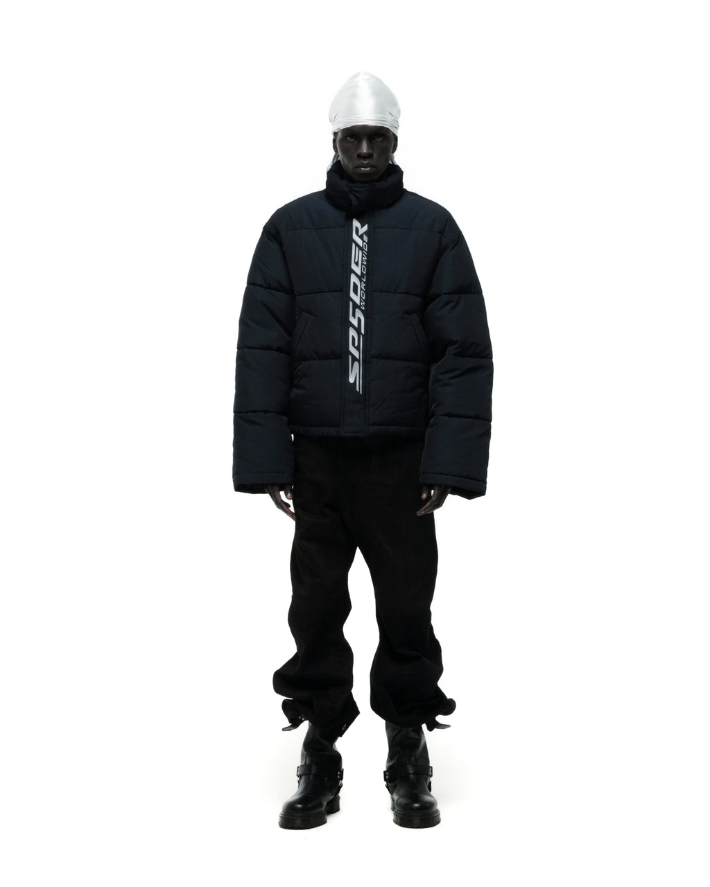 Dark blue TRACKHAWK puffer jacket with reflective "SP5DER WORLDWIDE" text, worn by a model.