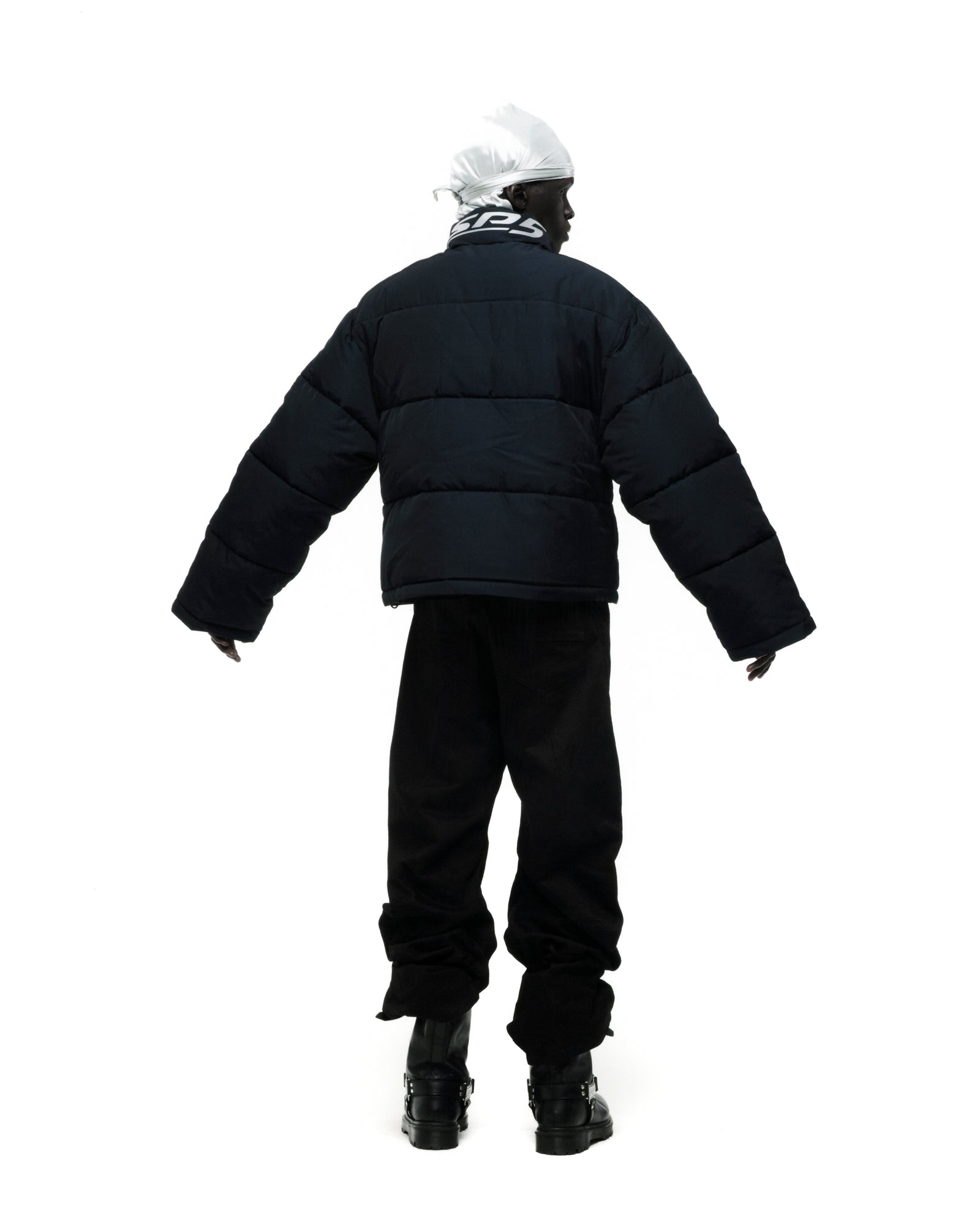 Black TRACKHAWK puffer jacket with reflective text, worn by a person facing away.