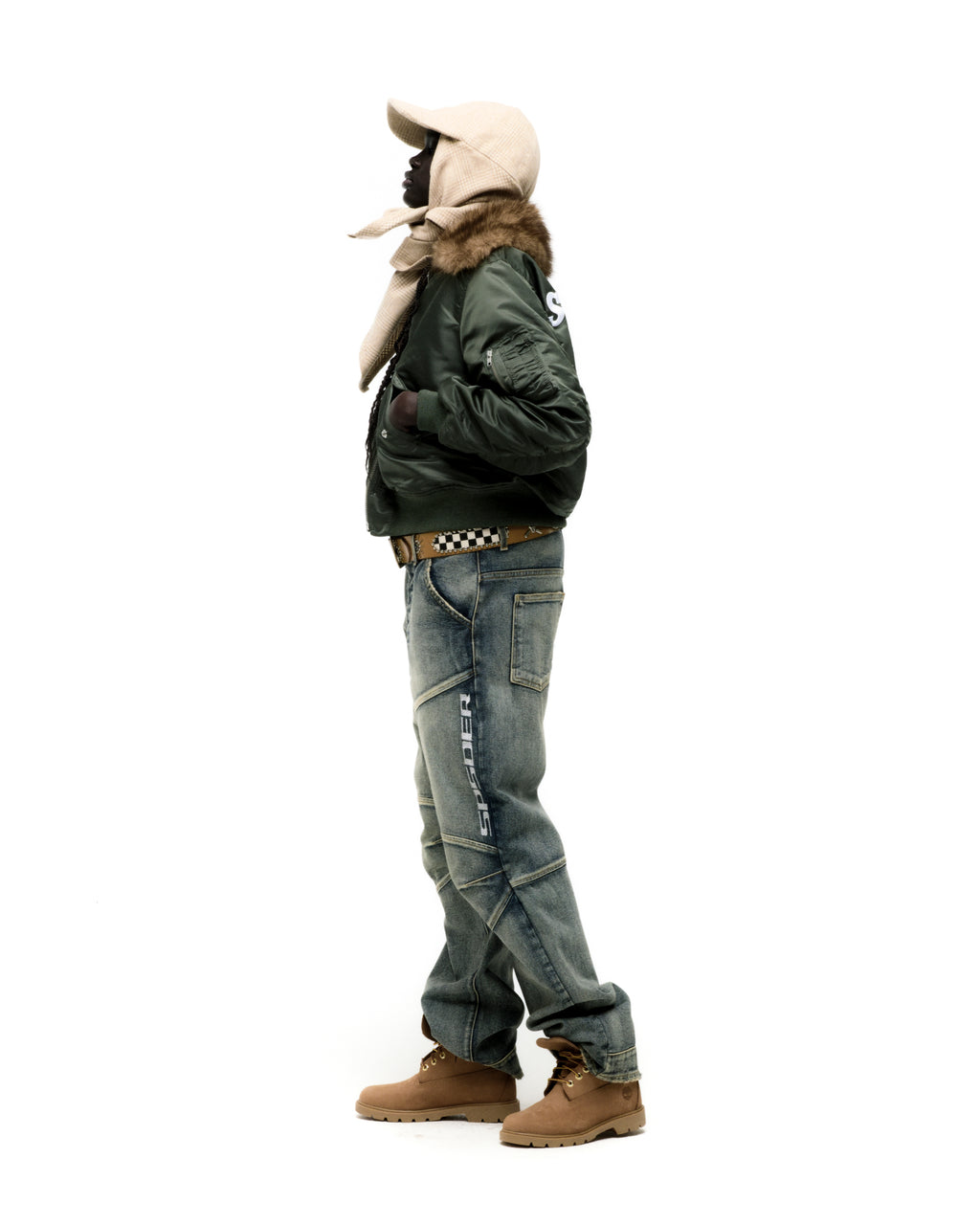 Green nylon bomber jacket with faux fur collar and SP5DER graphic, worn with jeans and boots.