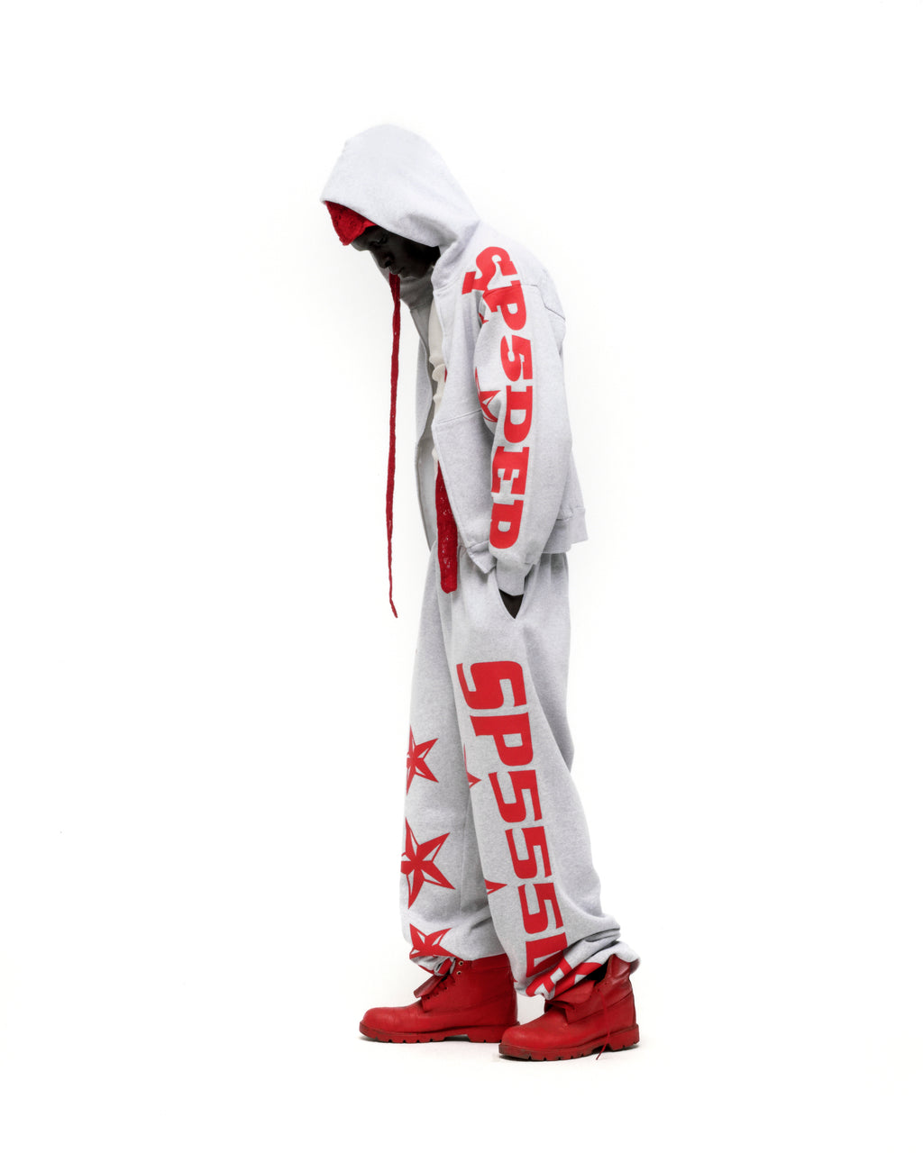 Grey MX555 ZIP HOODIE and sweatpants with red SP5DER print and stars, worn by a person with red boots.