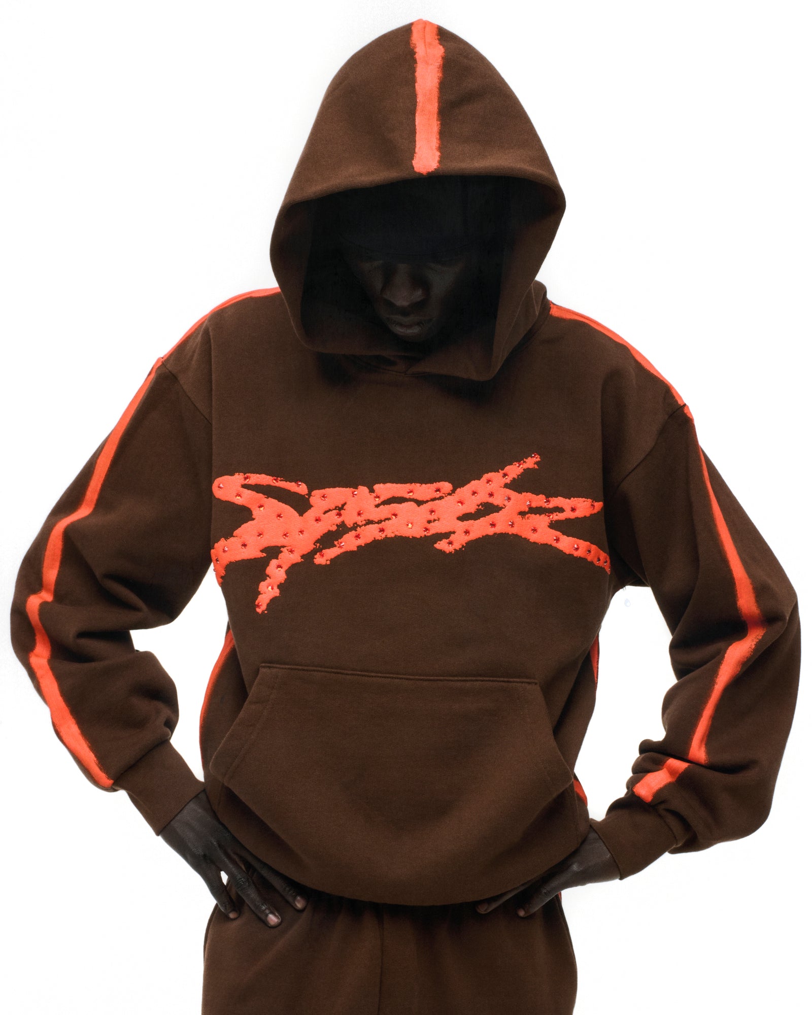 Brown cotton fleece hoodie with "SP5DER" logo, flaming "5" on back (not visible), and orange sprayed stripes.