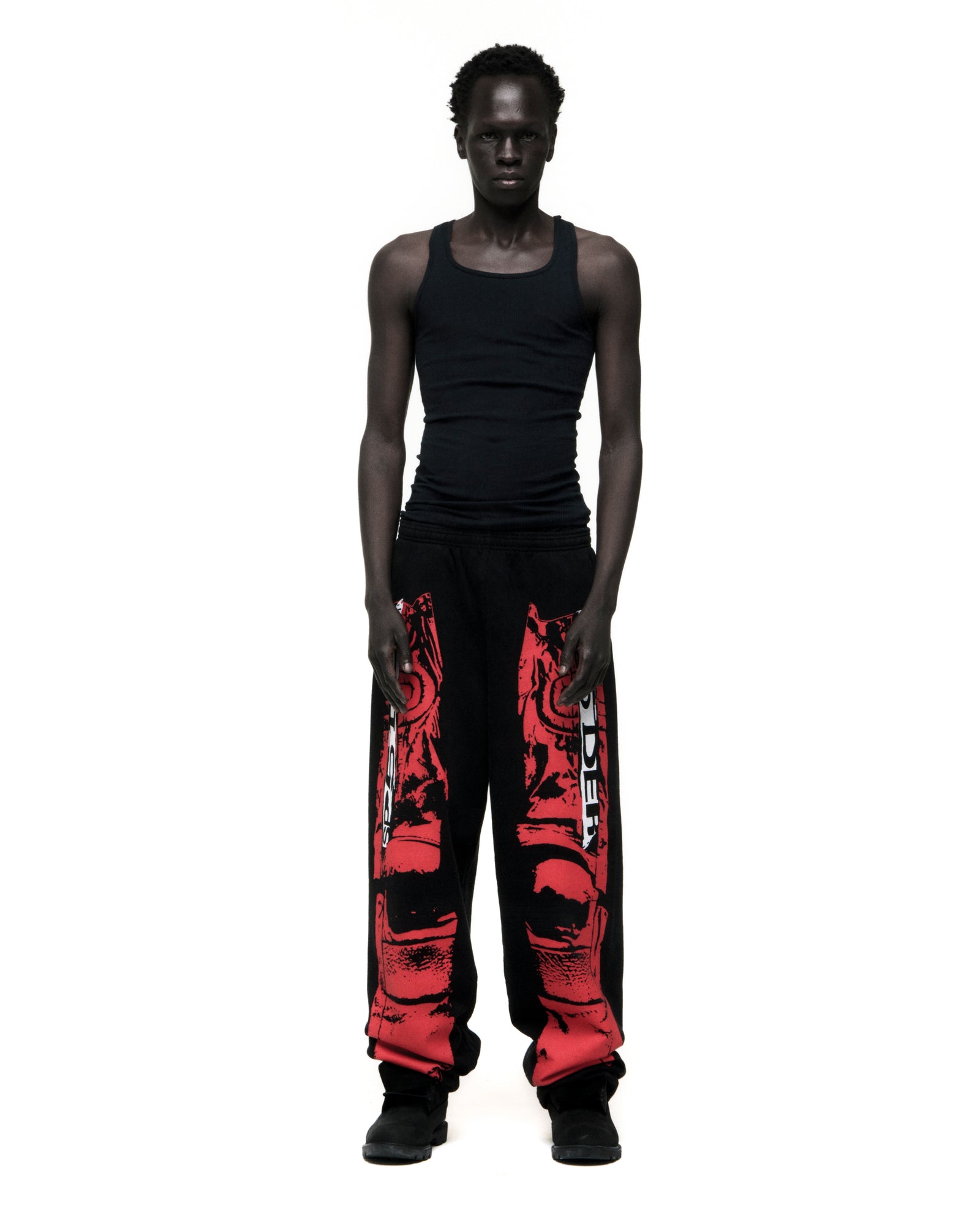Man in black JP5 Moto Sweatpants with red painted design, wide-leg, and black tank top.
