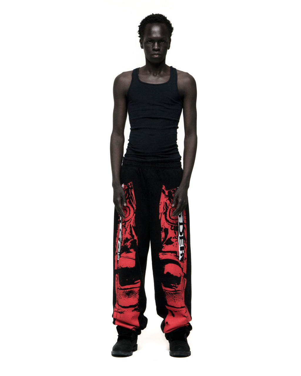 Man in black JP5 Moto Sweatpants with red painted design, wide-leg, and black tank top.