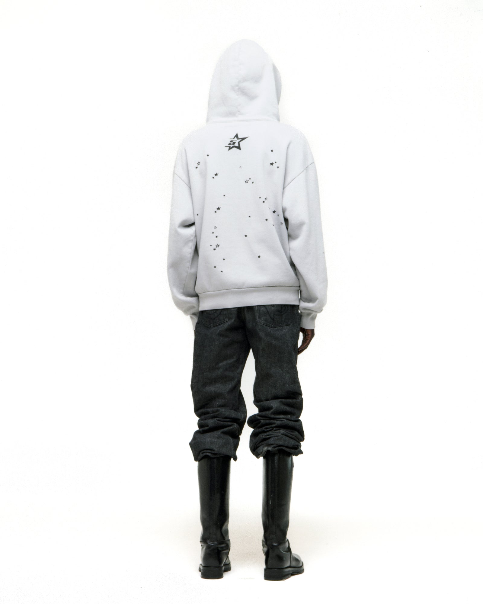 White STAR GIRL HOODIE with scattered star print on back, paired with dark jeans and black boots.