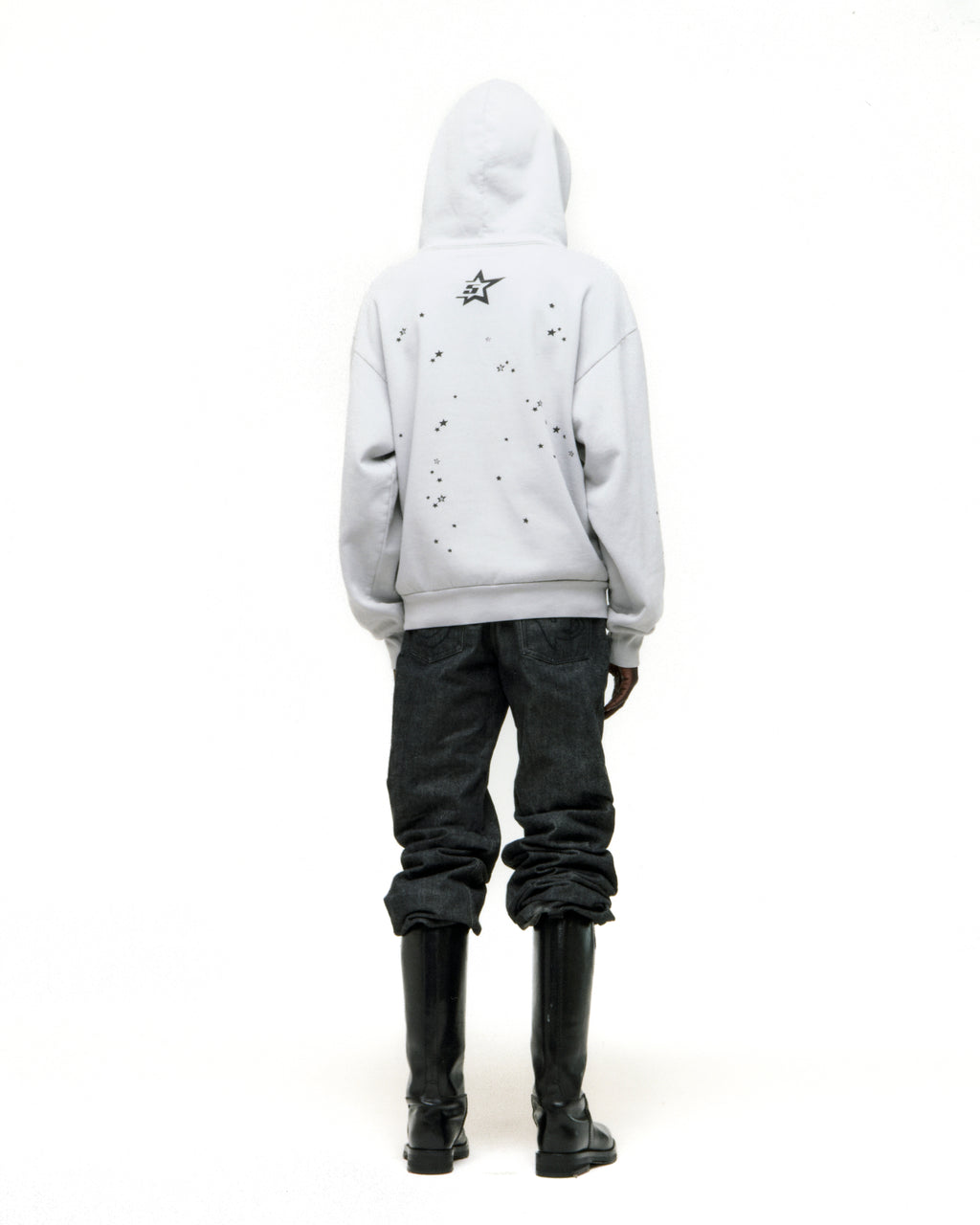 White STAR GIRL HOODIE with scattered star print on back, paired with dark jeans and black boots.