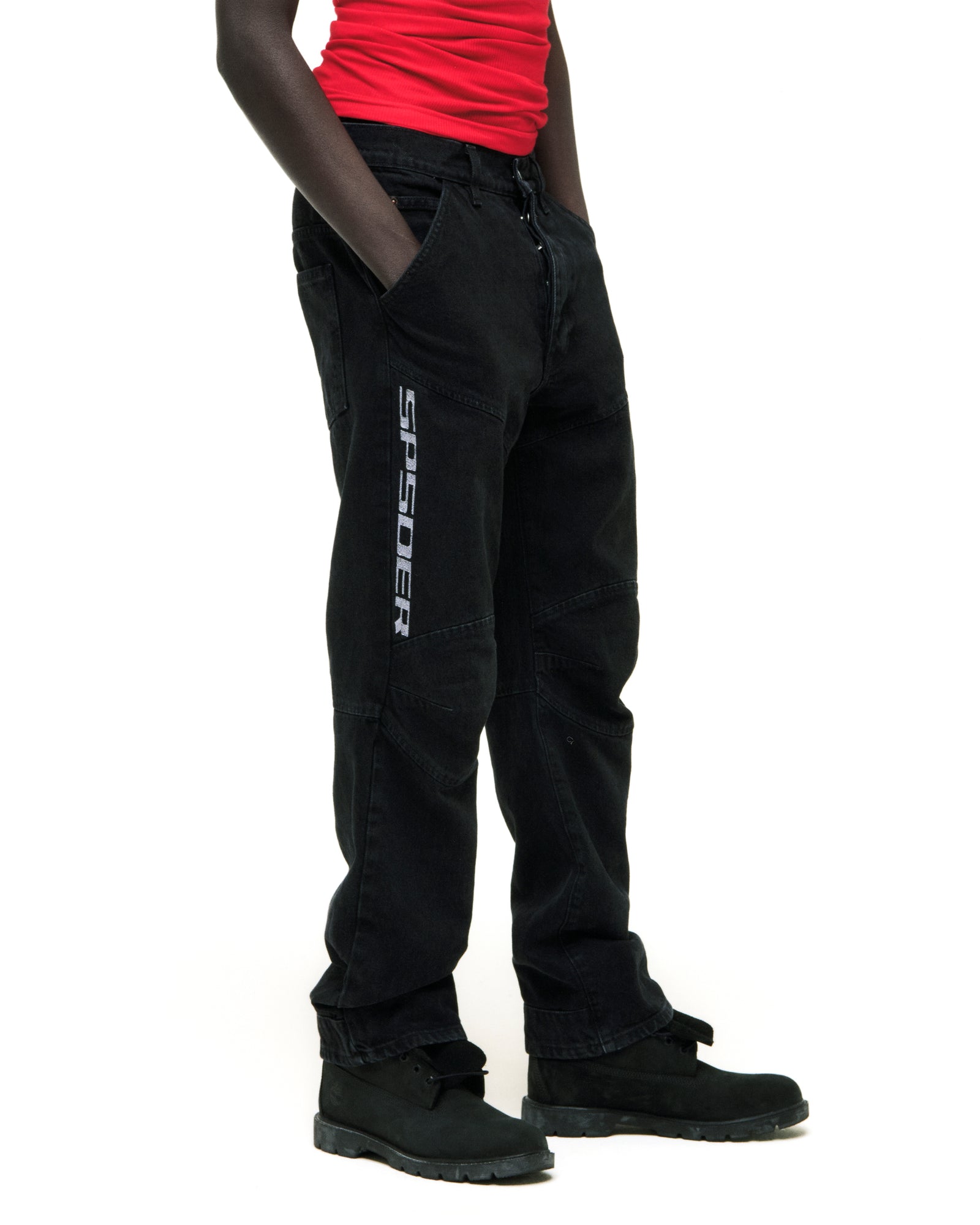 Black faded denim pants with "SP5DER" logo, paneled knees, and distressed details.