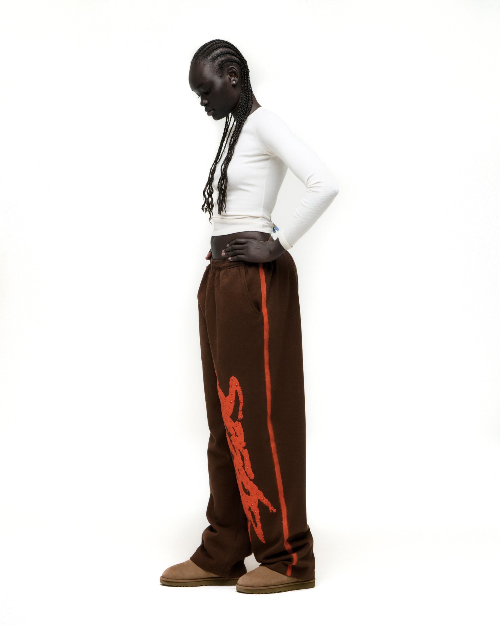 Brown cotton fleece sweatpants with "SP5DER" rhinestone logo and sprayed orange side stripe.