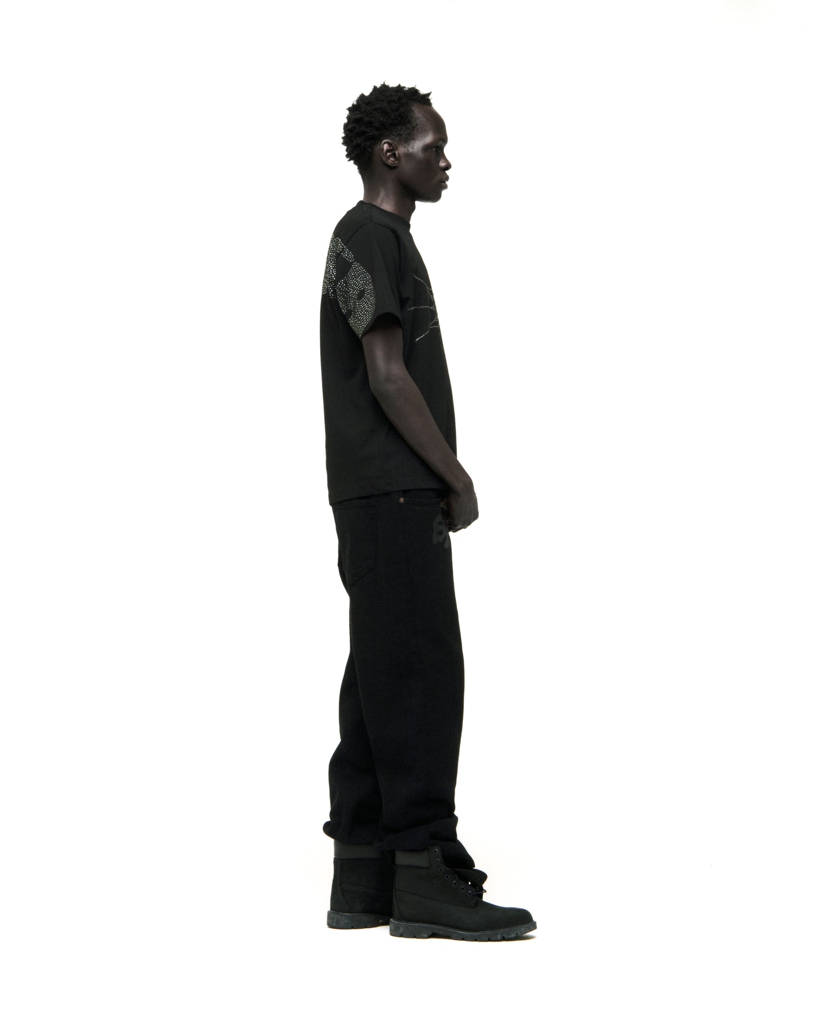 Black cotton tee with rhinestone graphic, worn by a man in profile.