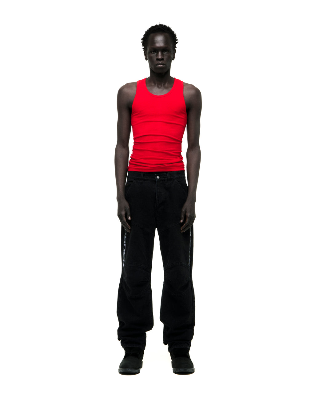 Man in black faded wash denim pants with "SP5DER" logo, paneled knees, and distressed details.