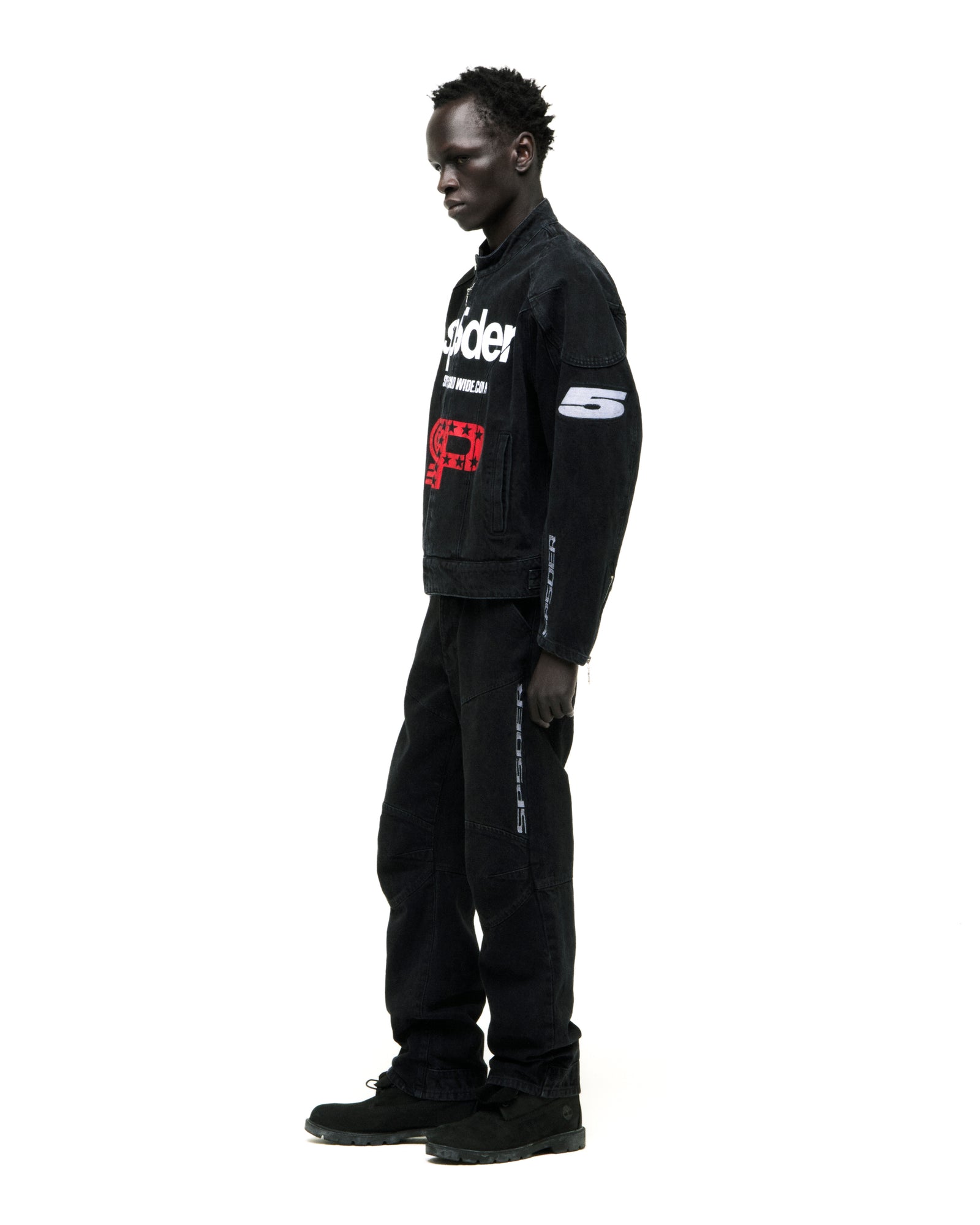 Faded black denim jacket with SP5DER chest print, star back print, patches, and embroidery.