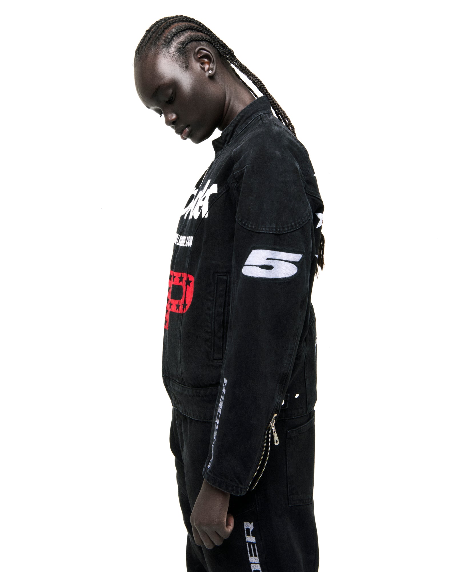 Faded black denim jacket with SP5DER print, star print, shoulder panels, and arm patches.