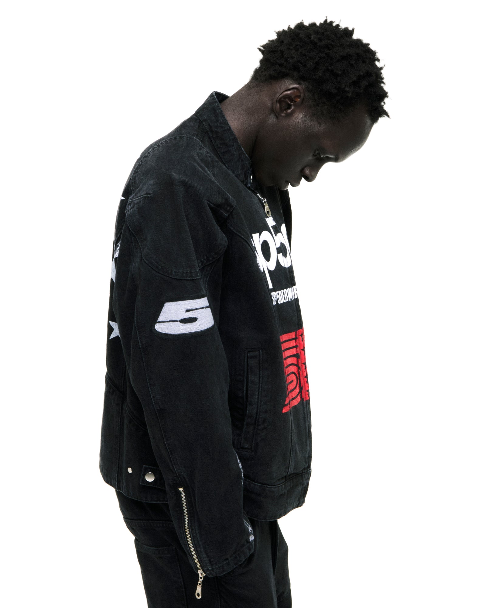 Faded black denim jacket with SP5DER chest print, star back print, arm patches, and cuff embroidery.