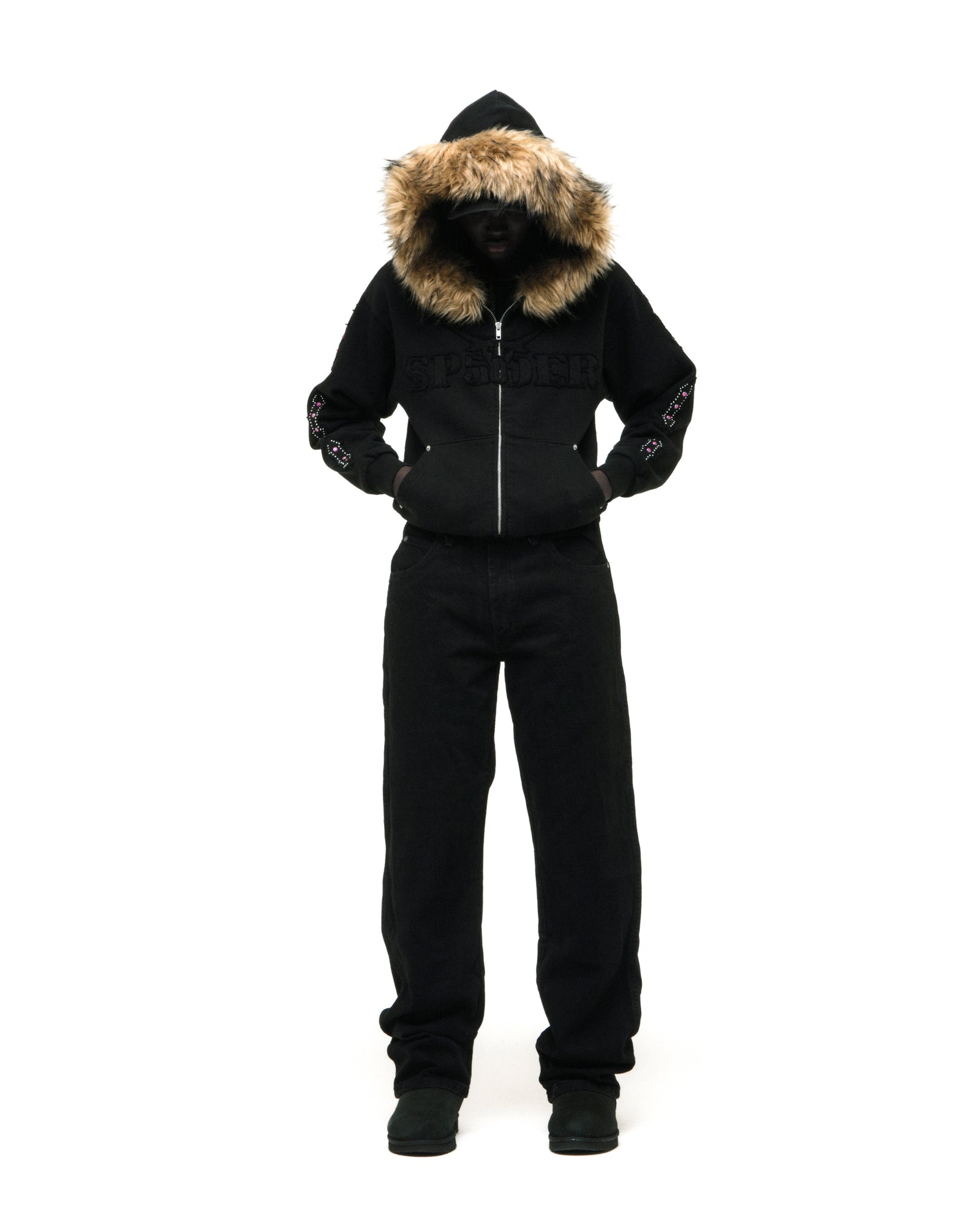 Black 13oz cotton fleece Garibaldi zip-up with faux fur hood trim, SP5DER text patches, patterned sleeve accents, and studded pockets.