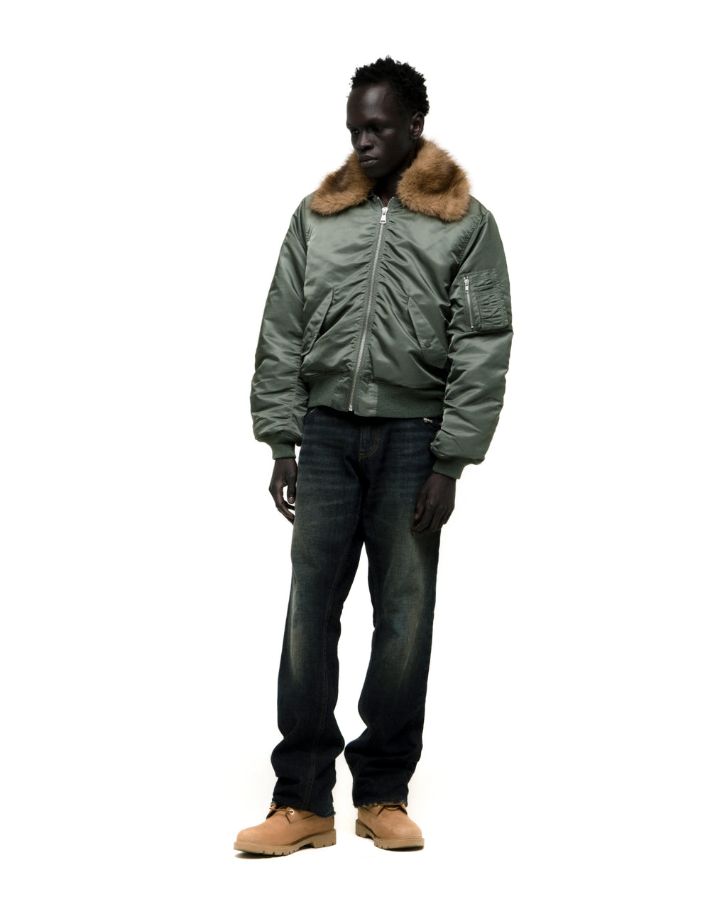 Green nylon bomber jacket with a brown faux fur collar, worn by a model.