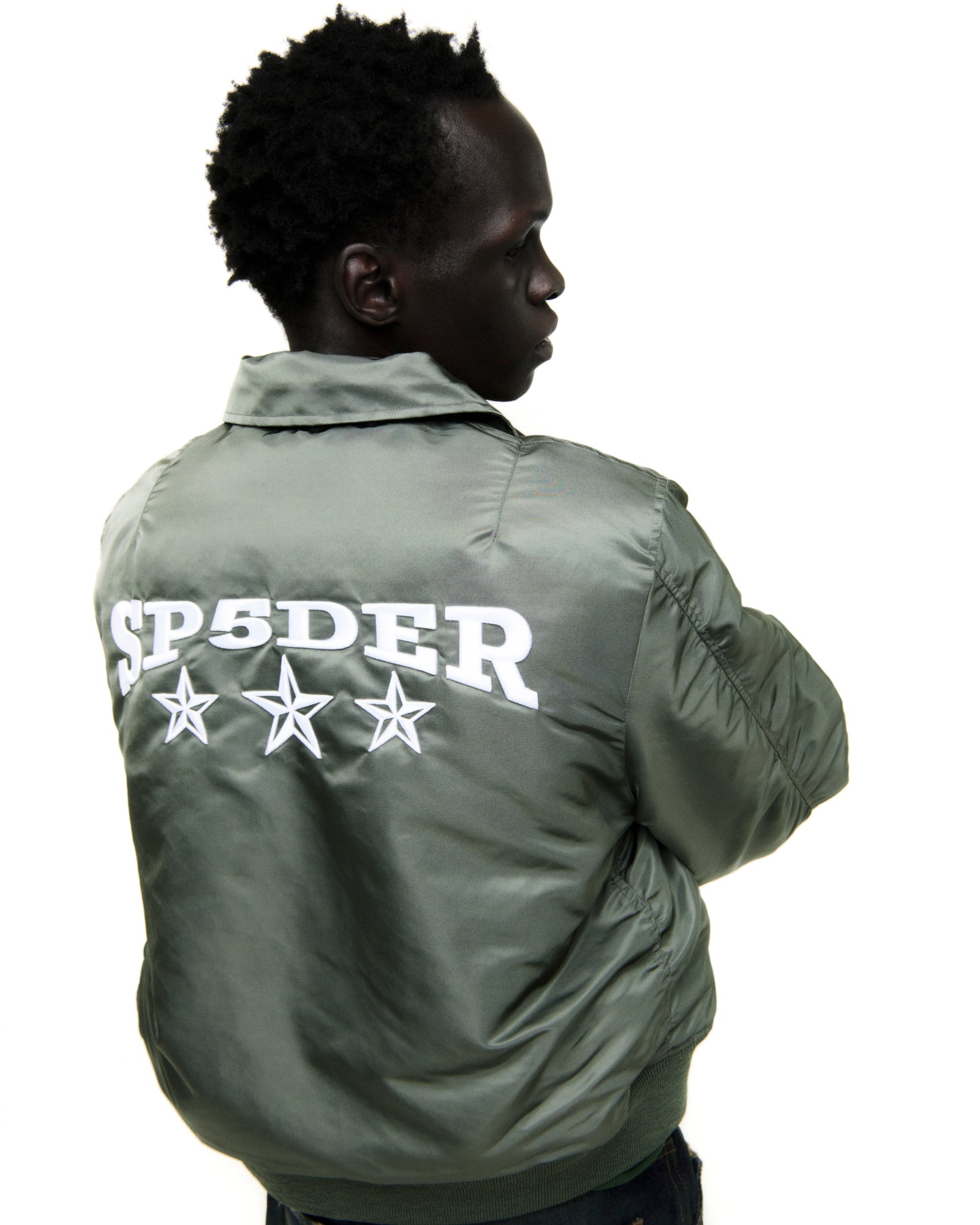Olive nylon bomber jacket with white "SP5DER" graphic and three stars on the back.