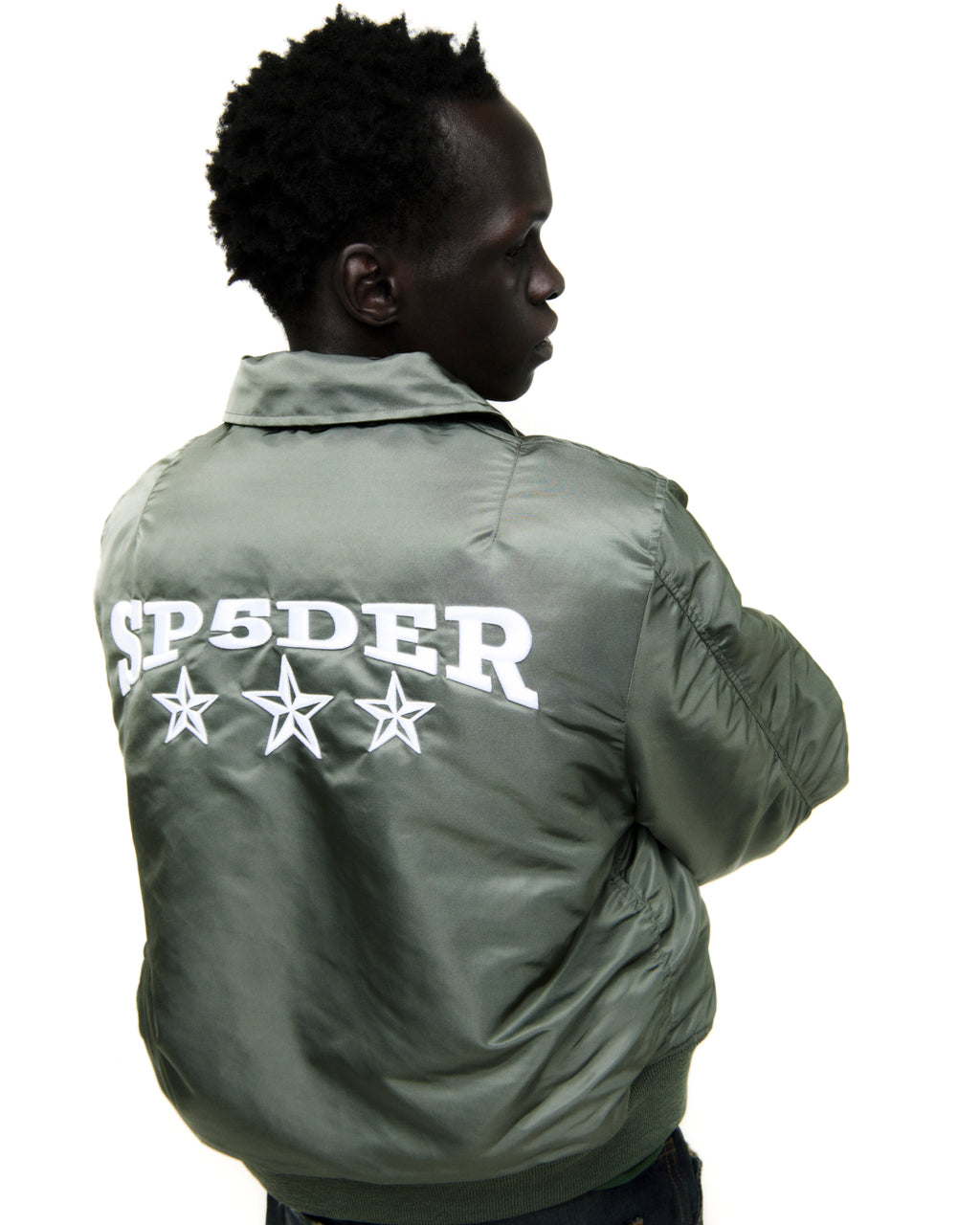 Olive nylon bomber jacket with white "SP5DER" graphic and three stars on the back.