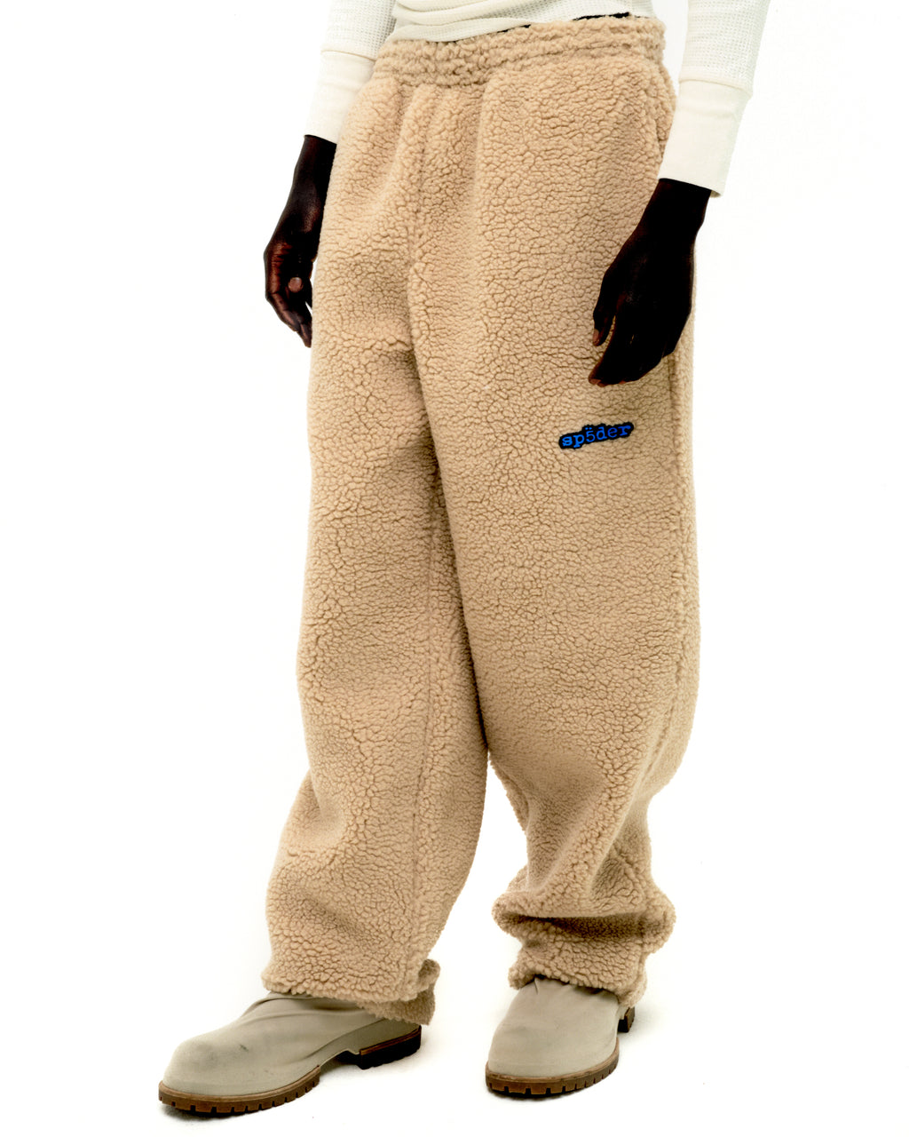 Beige sherpa fleece pant with blue rubberized logo patch on leg, elasticized waistband, and straight leg fit.