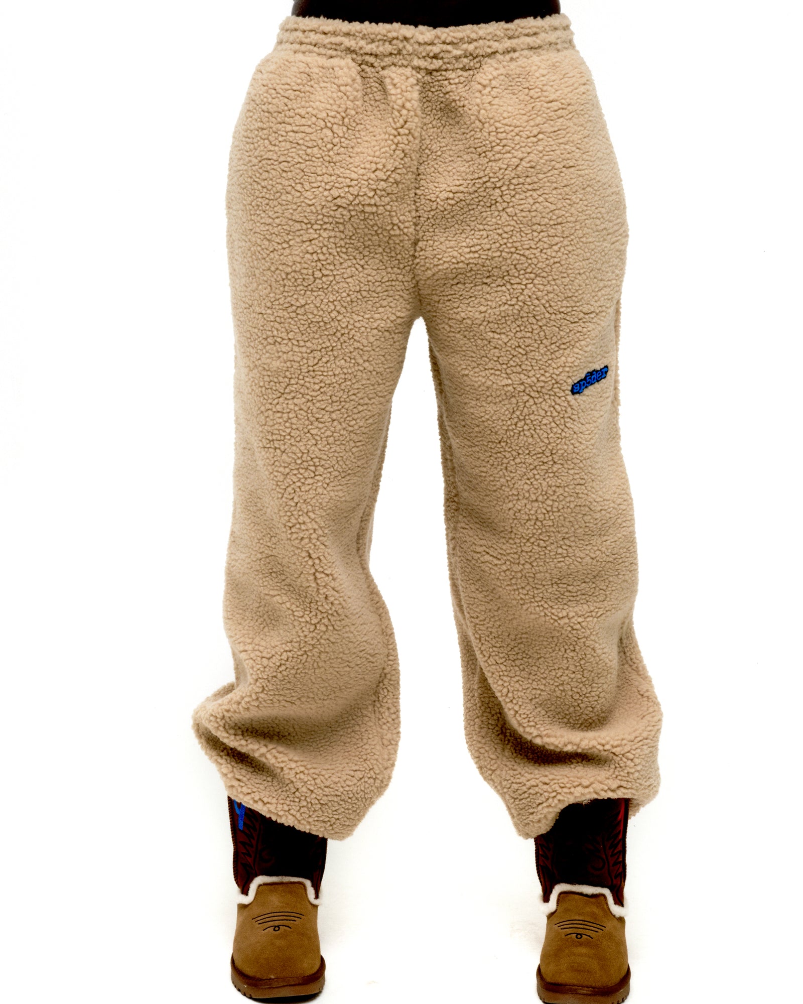 Tan sherpa fleece pant with elasticized drawstring waistband and blue rubberized logo patch on leg.
