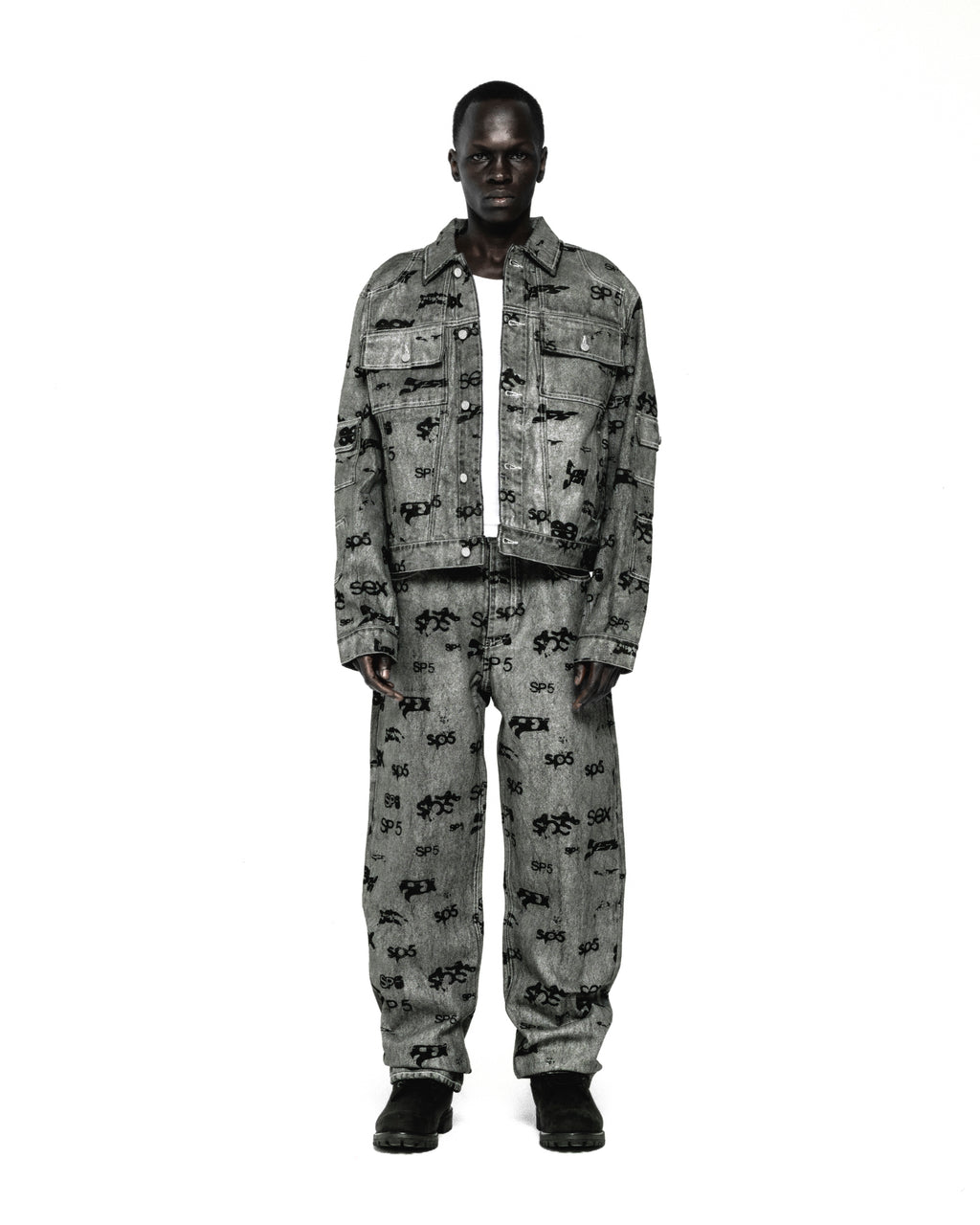 Model wearing a grey denim trucker jacket and matching pants with an all-over black print.