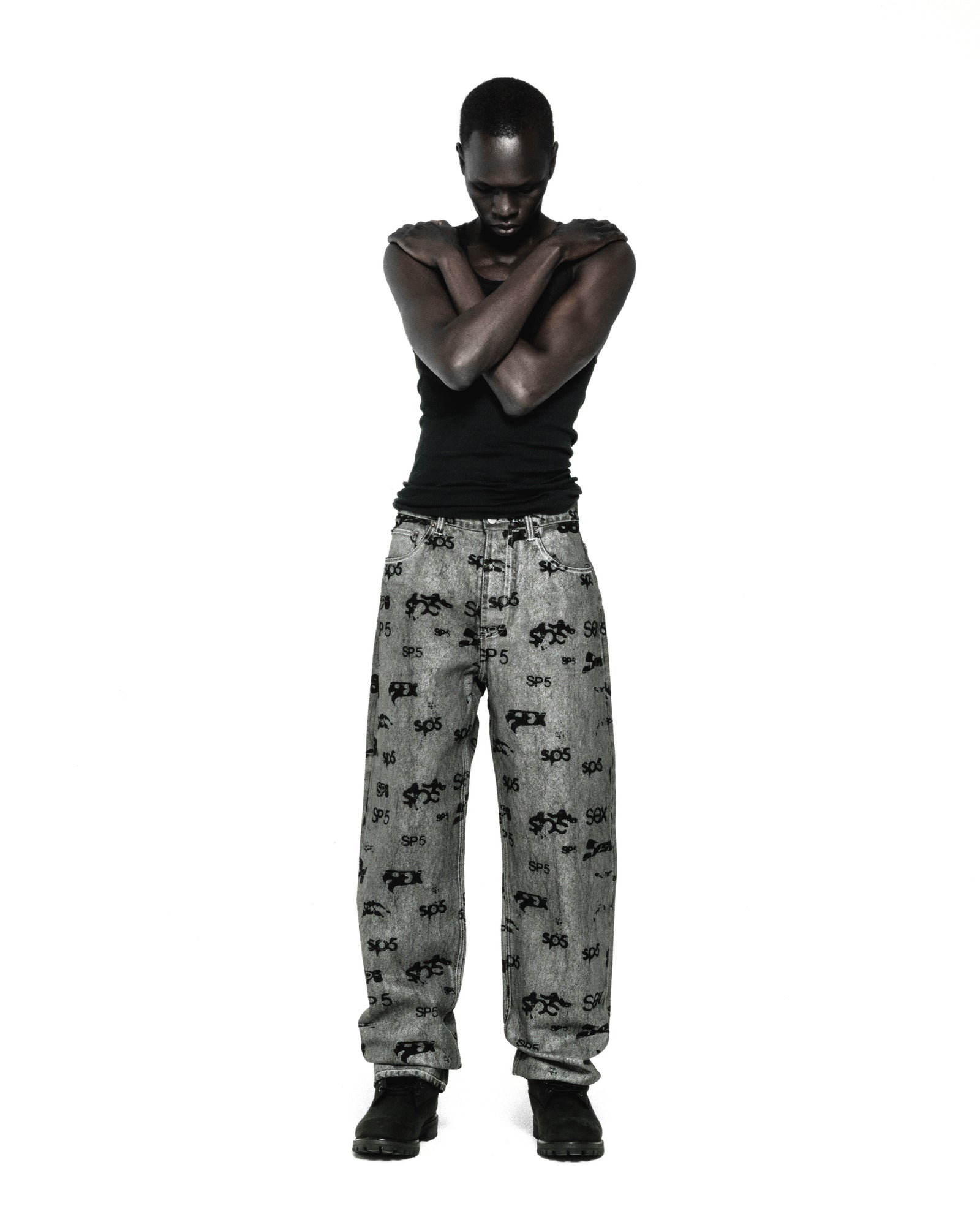 Model wearing grey denim pants with black all-over print, red contrast stitching, and straight leg fit.