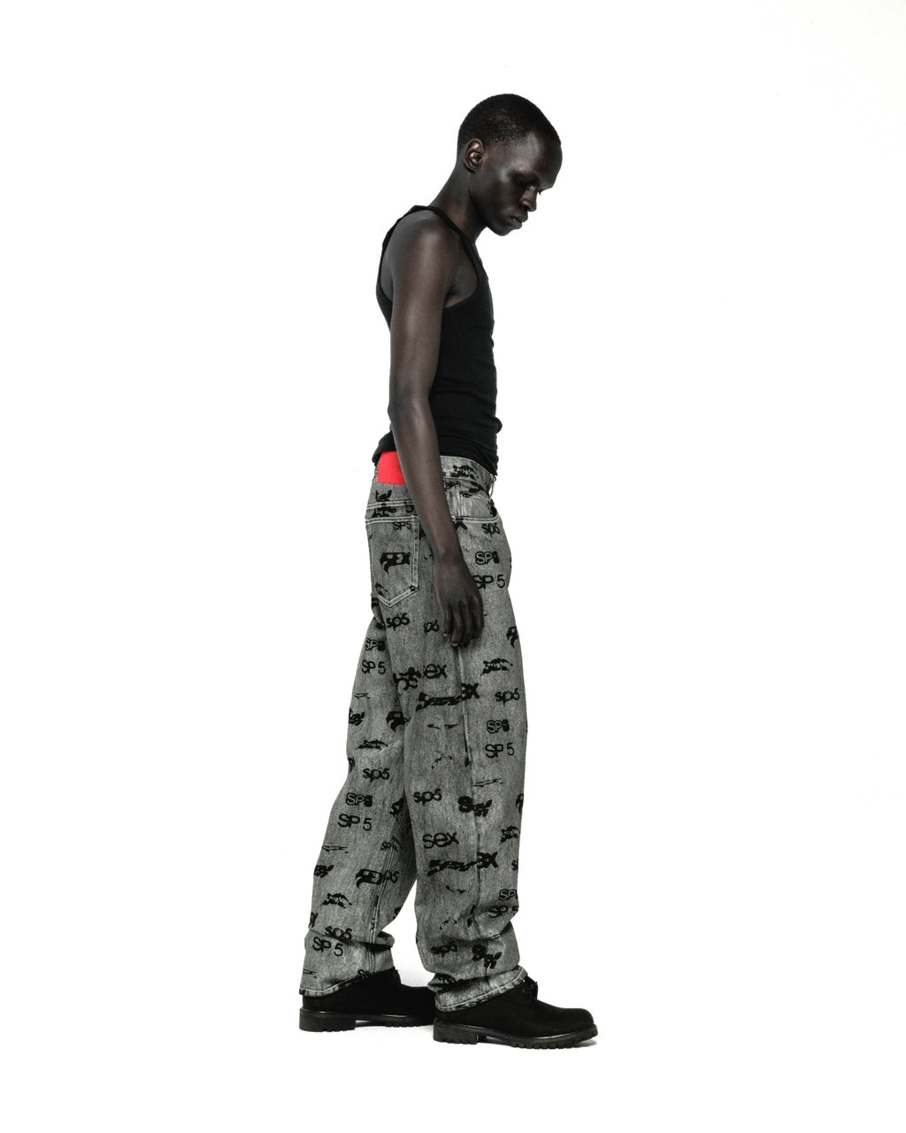 Grey denim pants with all-over "SEX" and "SP5DER" print, red contrast stitching, and straight leg fit.
