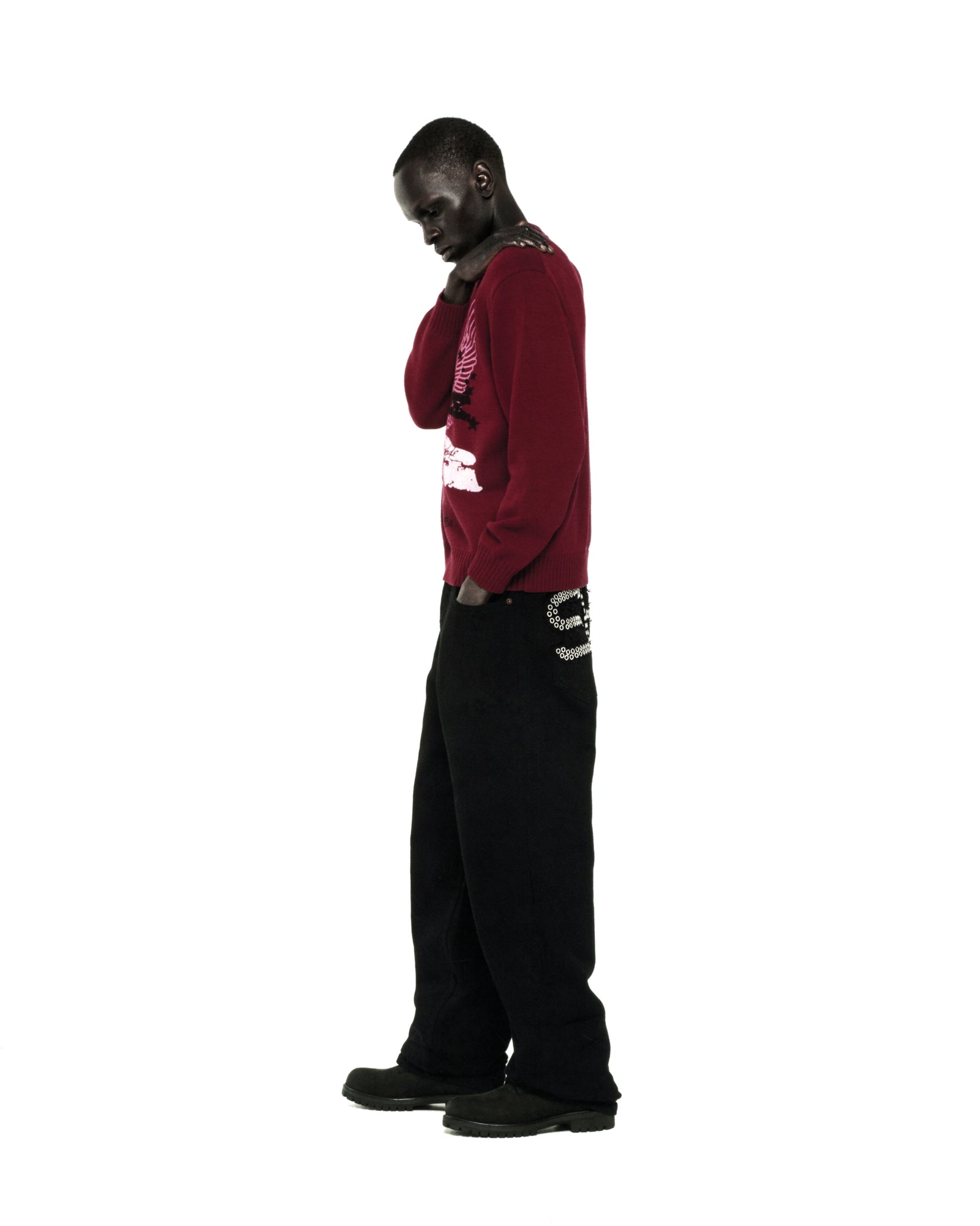 Red knit sweater with graphic print, ribbed collar, hem, and cuffs, worn by a man with black pants.