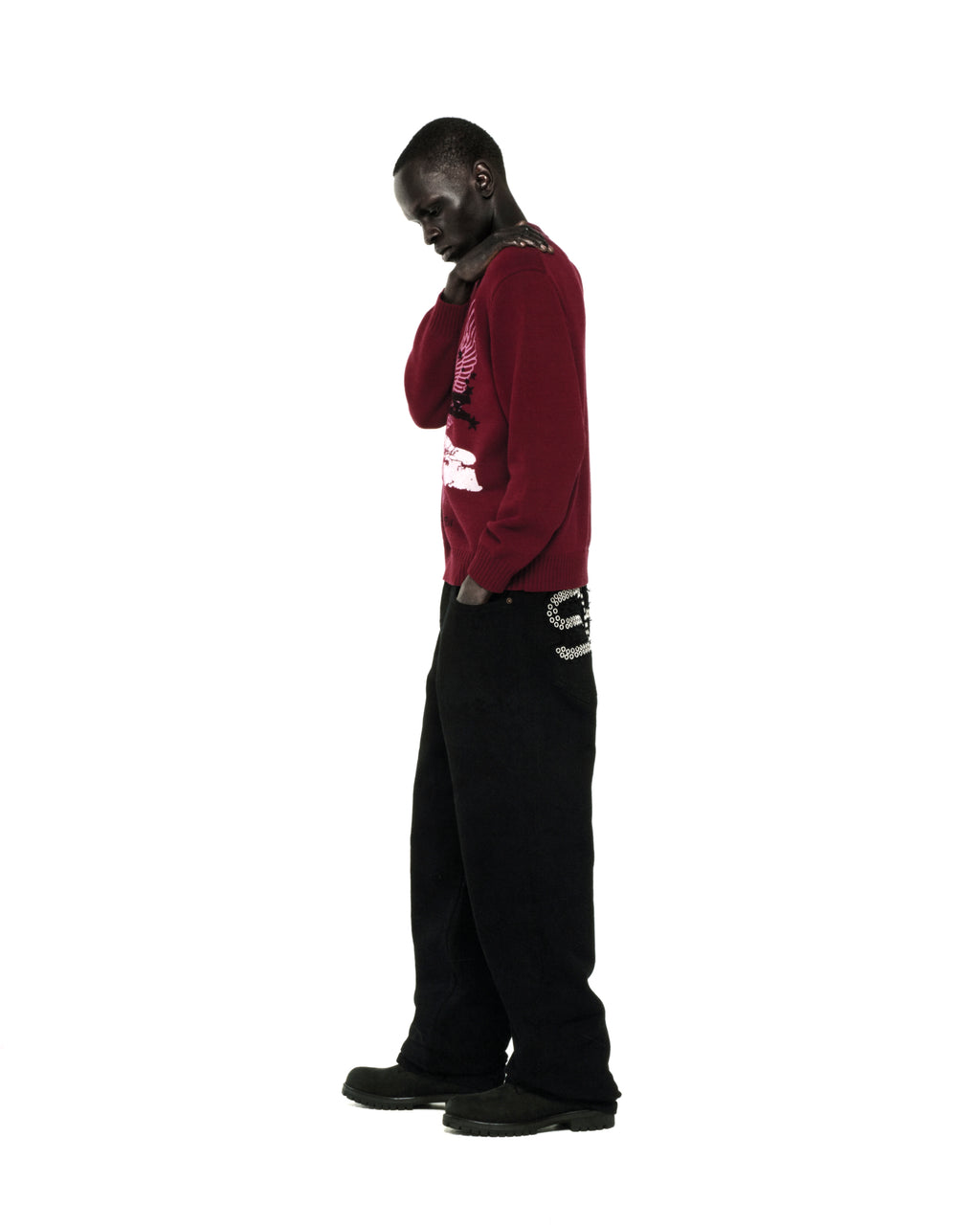 Red knit sweater with graphic print, ribbed collar, hem, and cuffs, worn by a man with black pants.