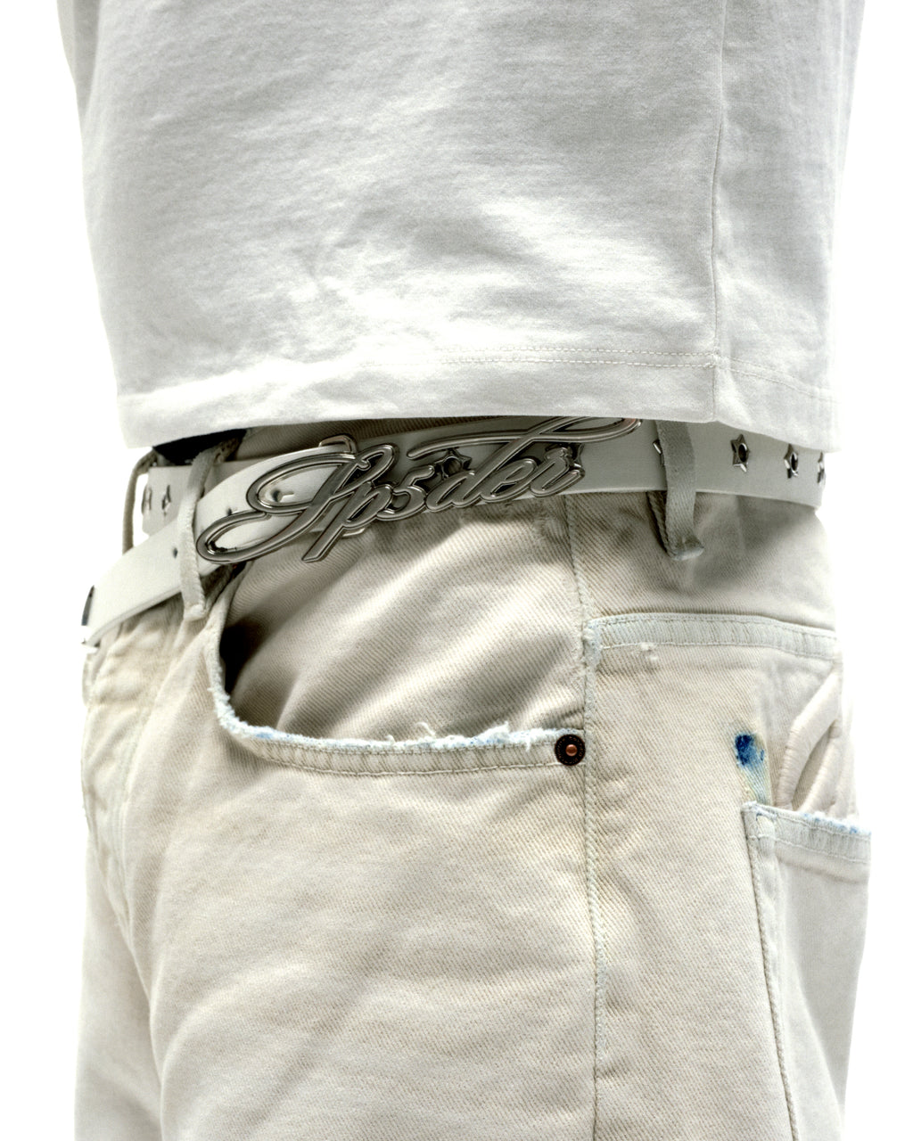 White leather R-05 Script Belt with cursive SP5DER buckle, studded star grommets, and silver tip.