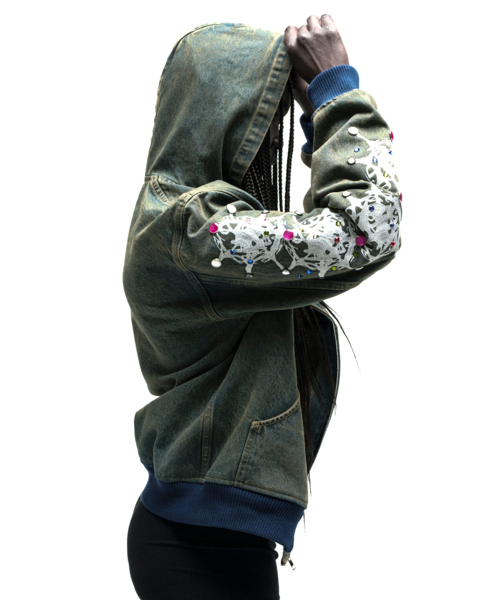 Faded denim hooded jacket with white web print and colorful rhinestone embellishments on sleeves.