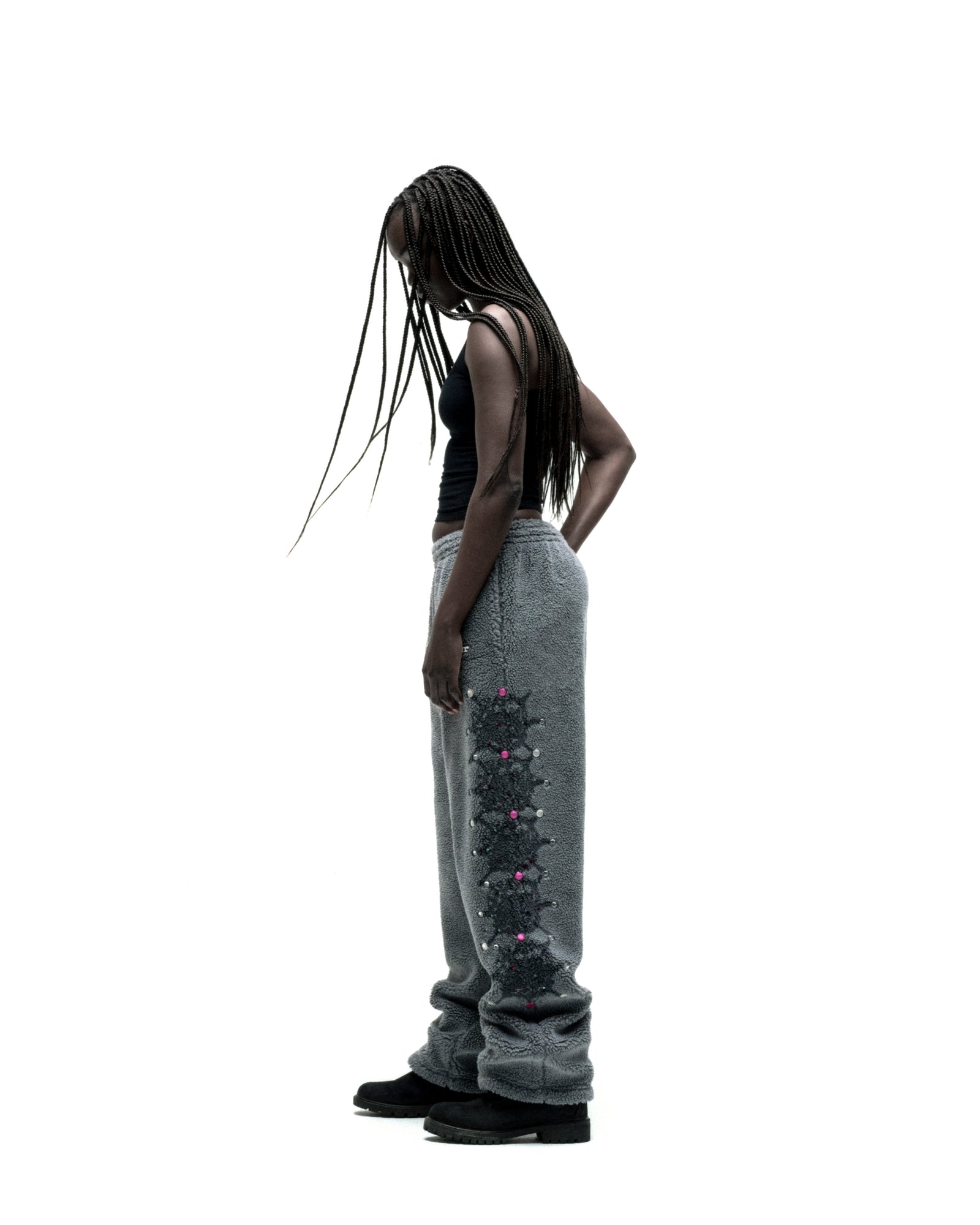 Woman in gray sherpa fleece pants with web print and rhinestone embellishments, elastic drawstring waist, and straight leg.