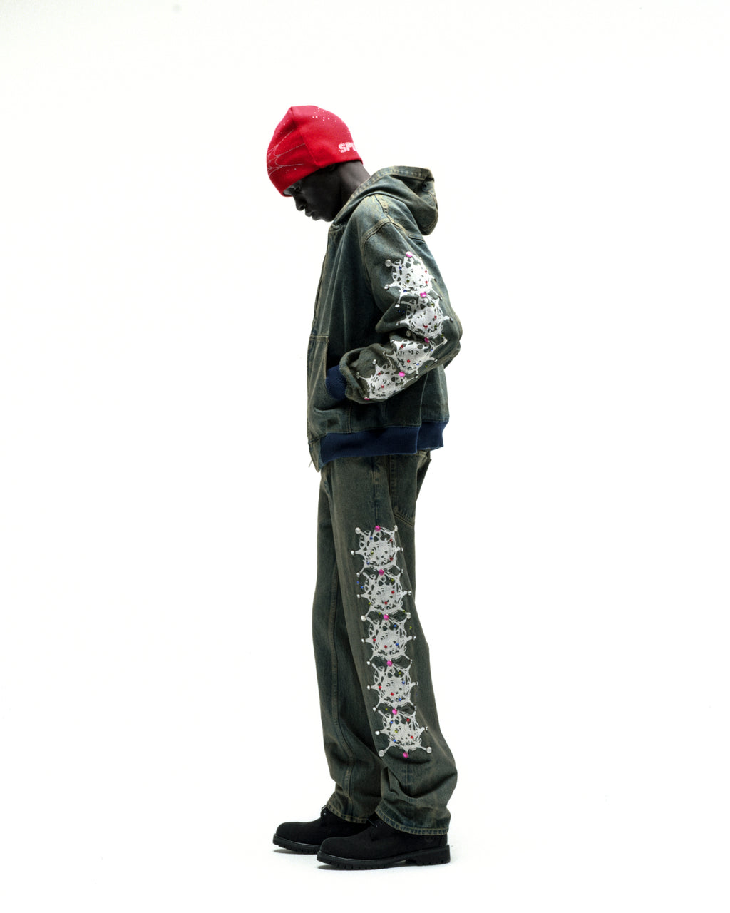 Faded denim hooded jacket with web print and rhinestone sleeves, paired with matching jeans.