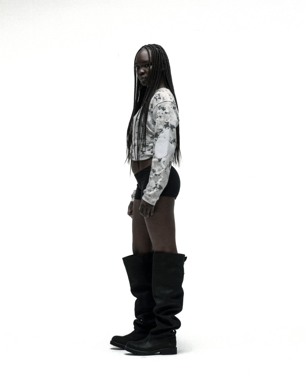 Woman in white star camo waffle knit thermal with Beluga print, black shorts, and tall black boots.