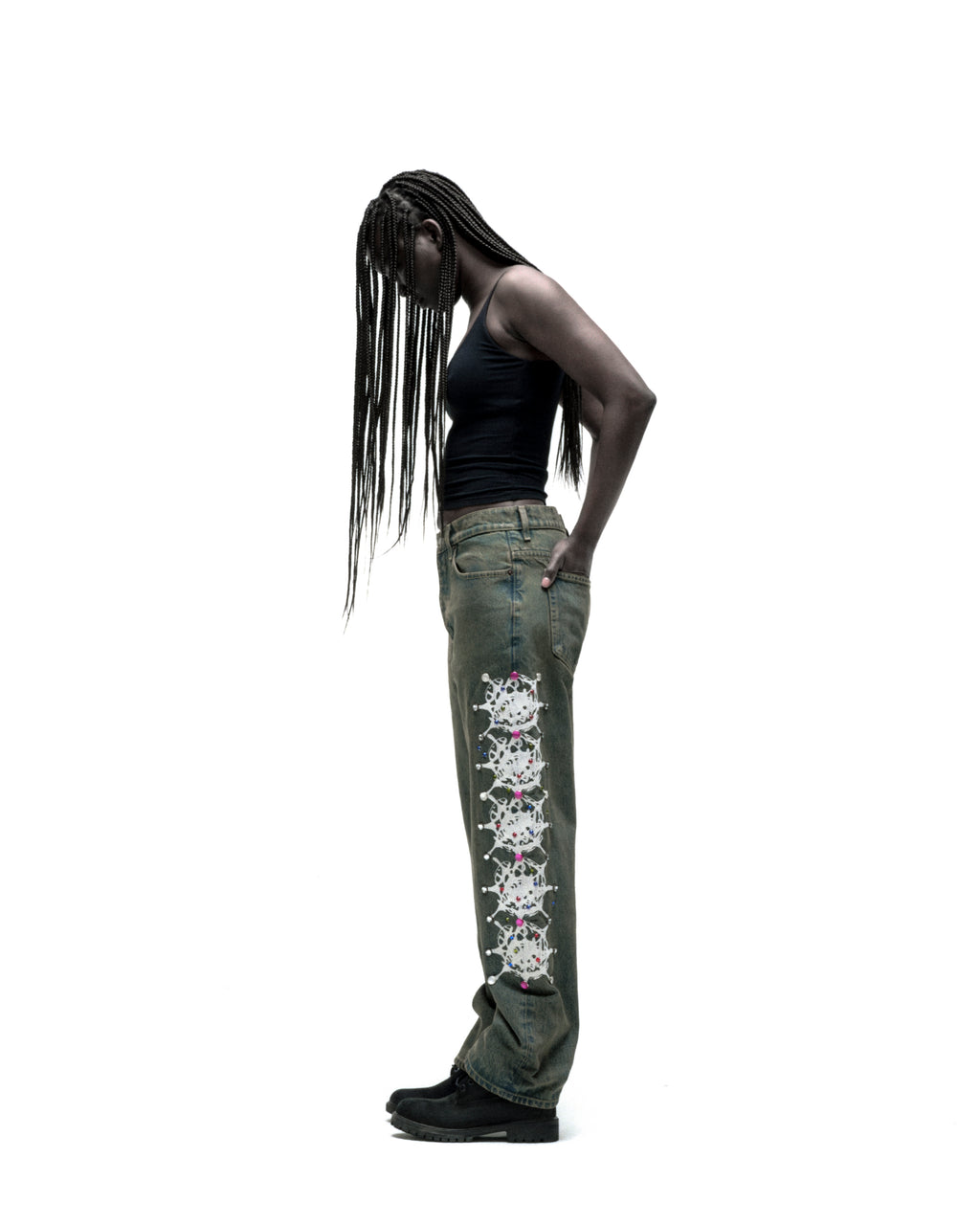 Vintage wash 13oz denim pants with web print and rhinestone embellishments down both legs, worn by a model.