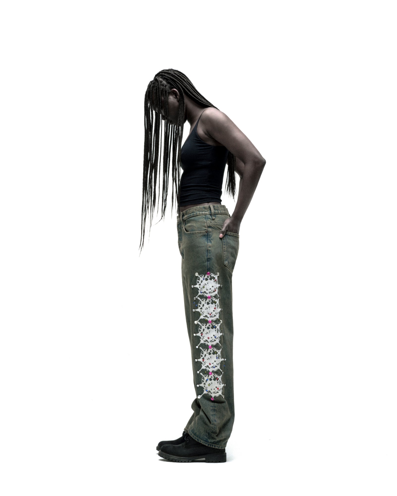 Vintage wash 13oz denim pants with web print and rhinestone embellishments down both legs, worn by a model.