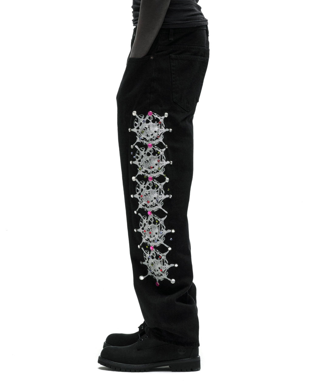 Black 13oz denim pants with vintage wash, featuring a silver web print and colorful rhinestone embellishments down the leg.